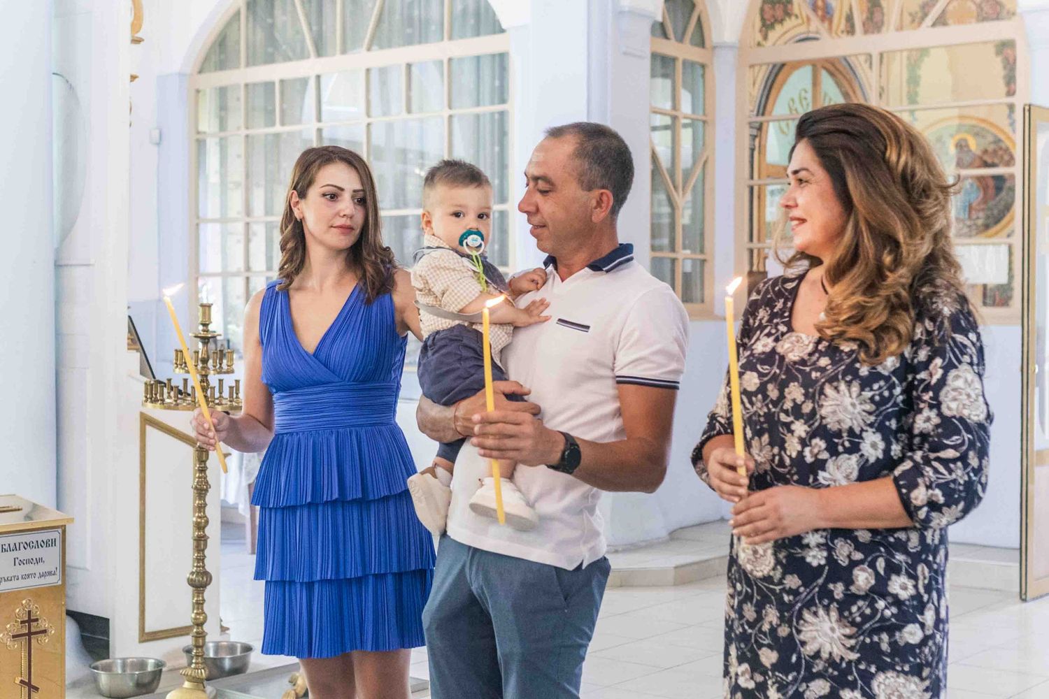 Family in coordinated blue and black outfits poses for photos in a bright elegant indoor setting.