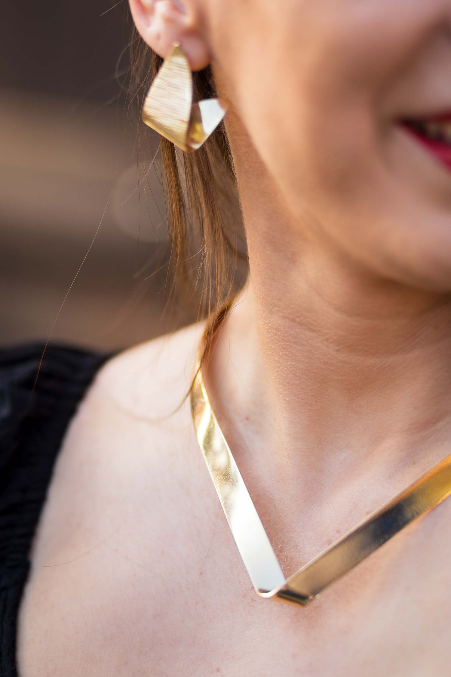 Close-up view of modern gold geometric statement jewelry including a matching necklace and earring set.