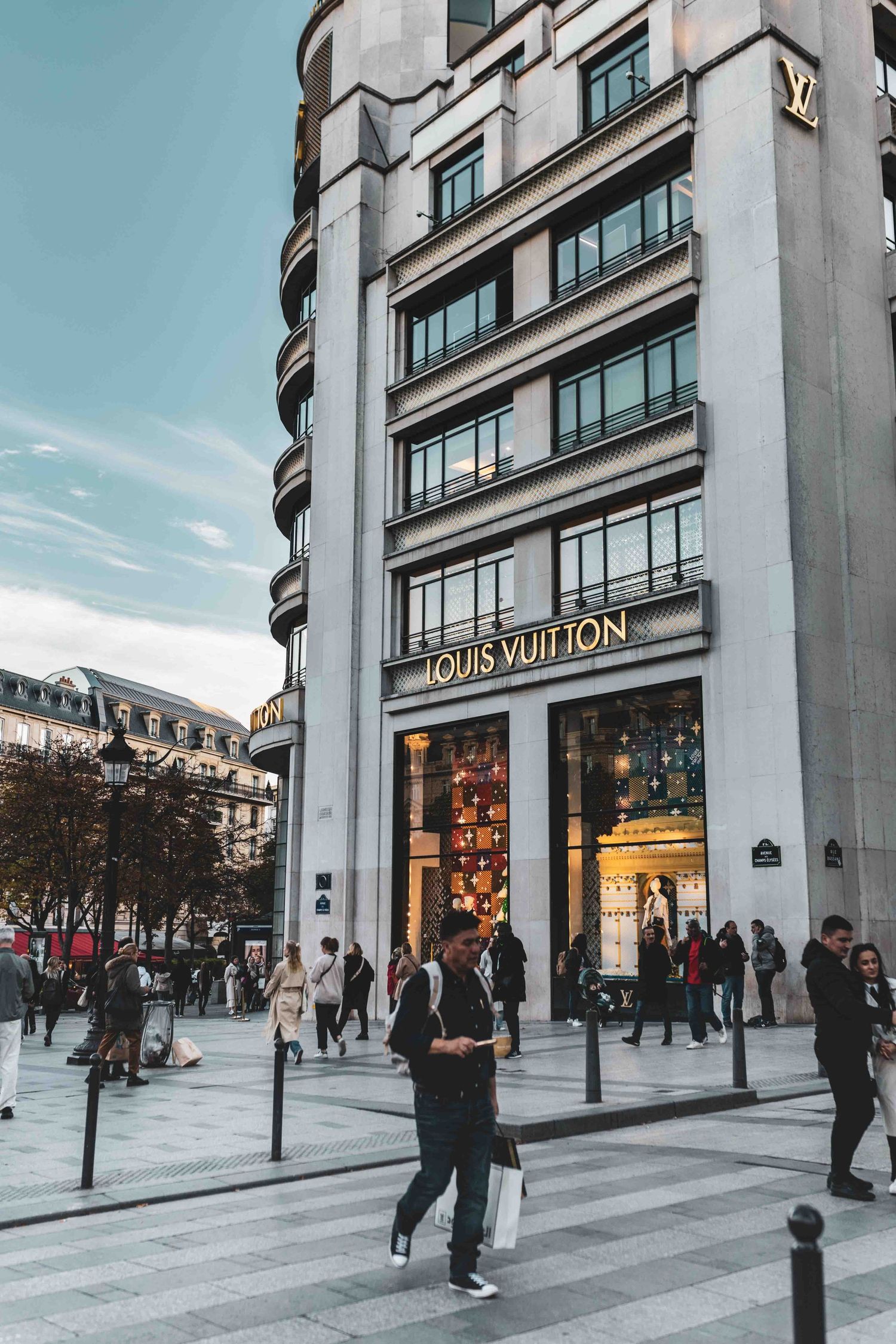 Louis Vuitton luxury retail store in an art deco style building with curved architecture on a busy Parisian street corner.