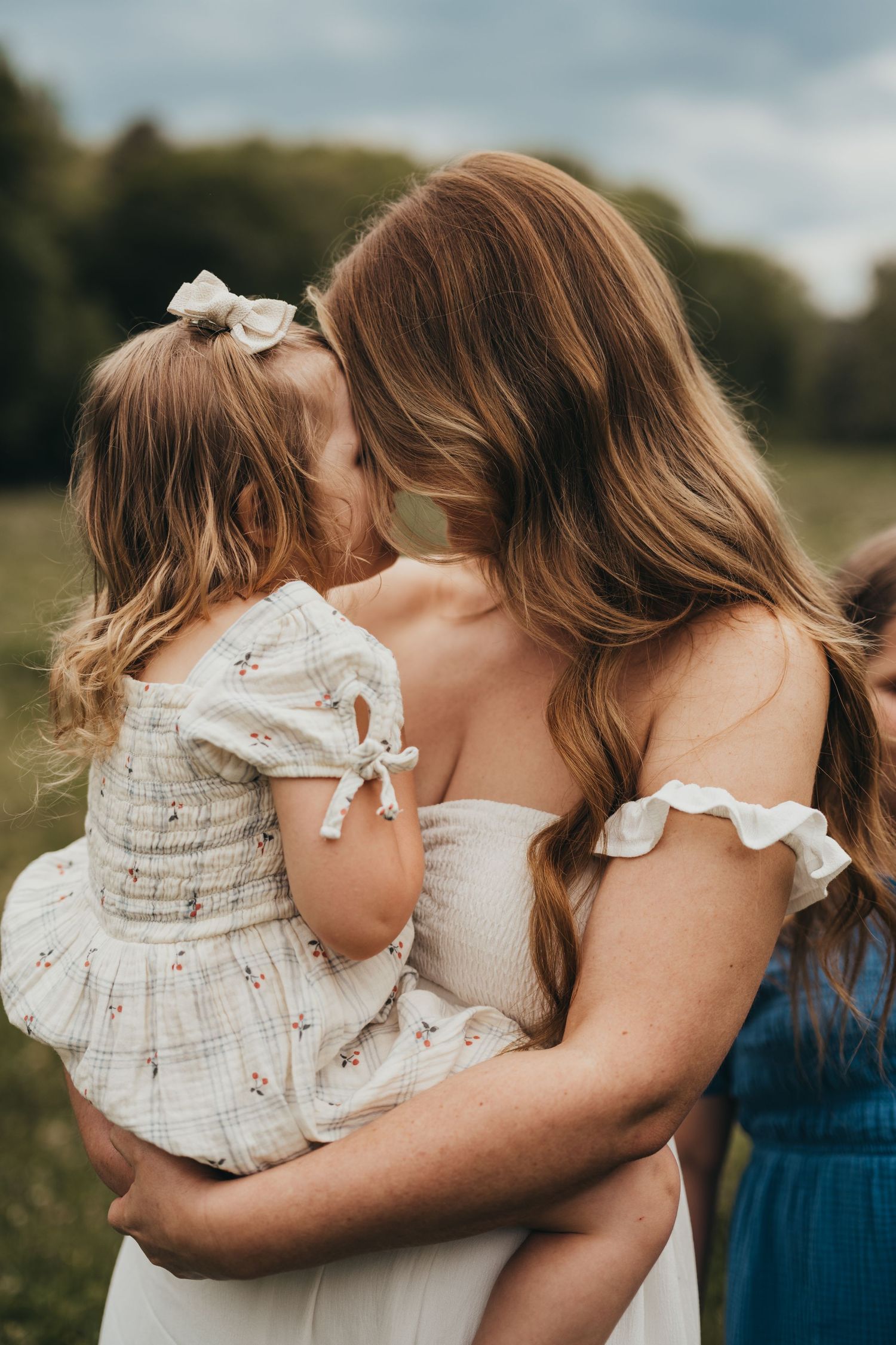 Tender family moment captured in soft natural lighting outdoors.