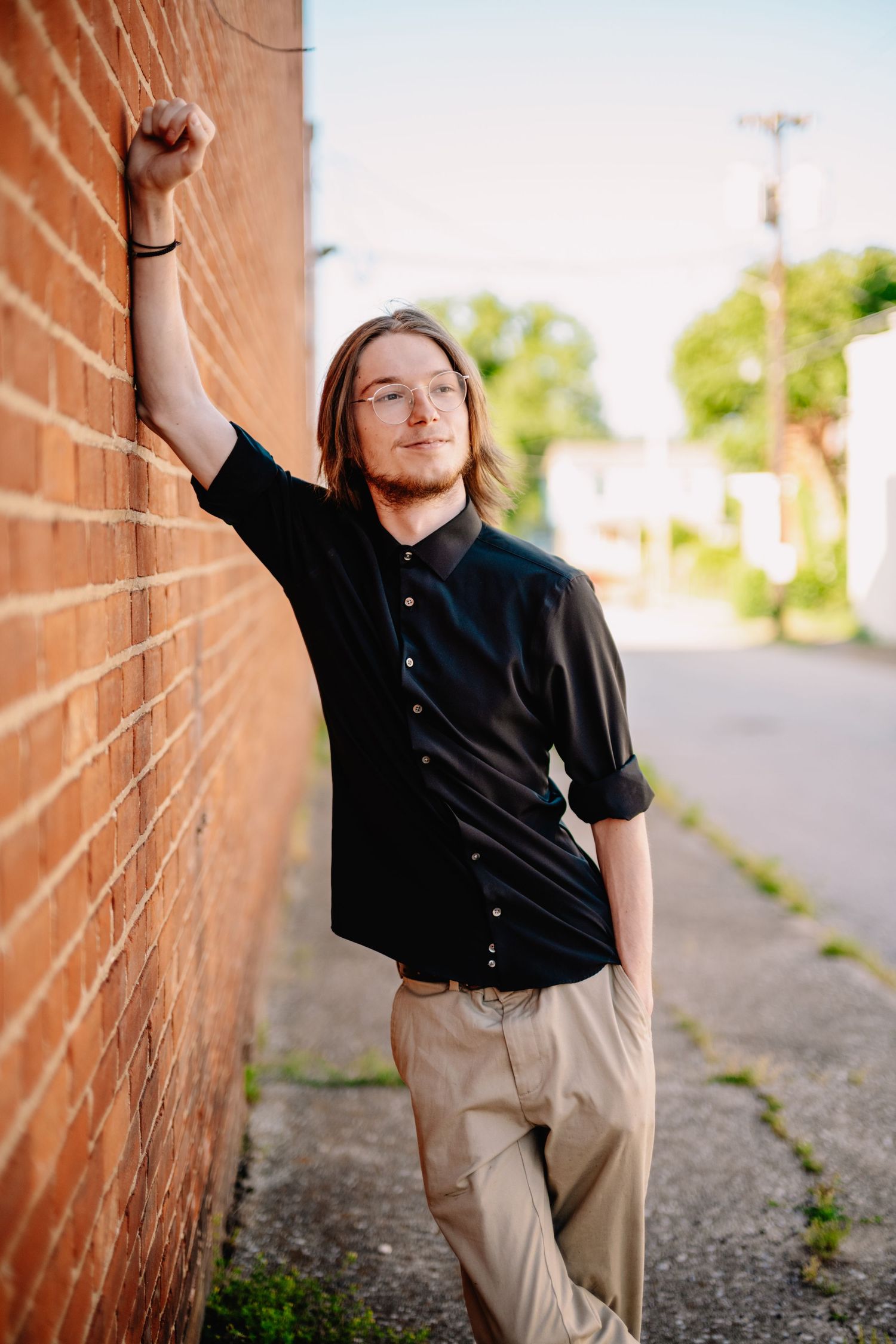 Creative poses against brick wall in natural outdoor lighting.