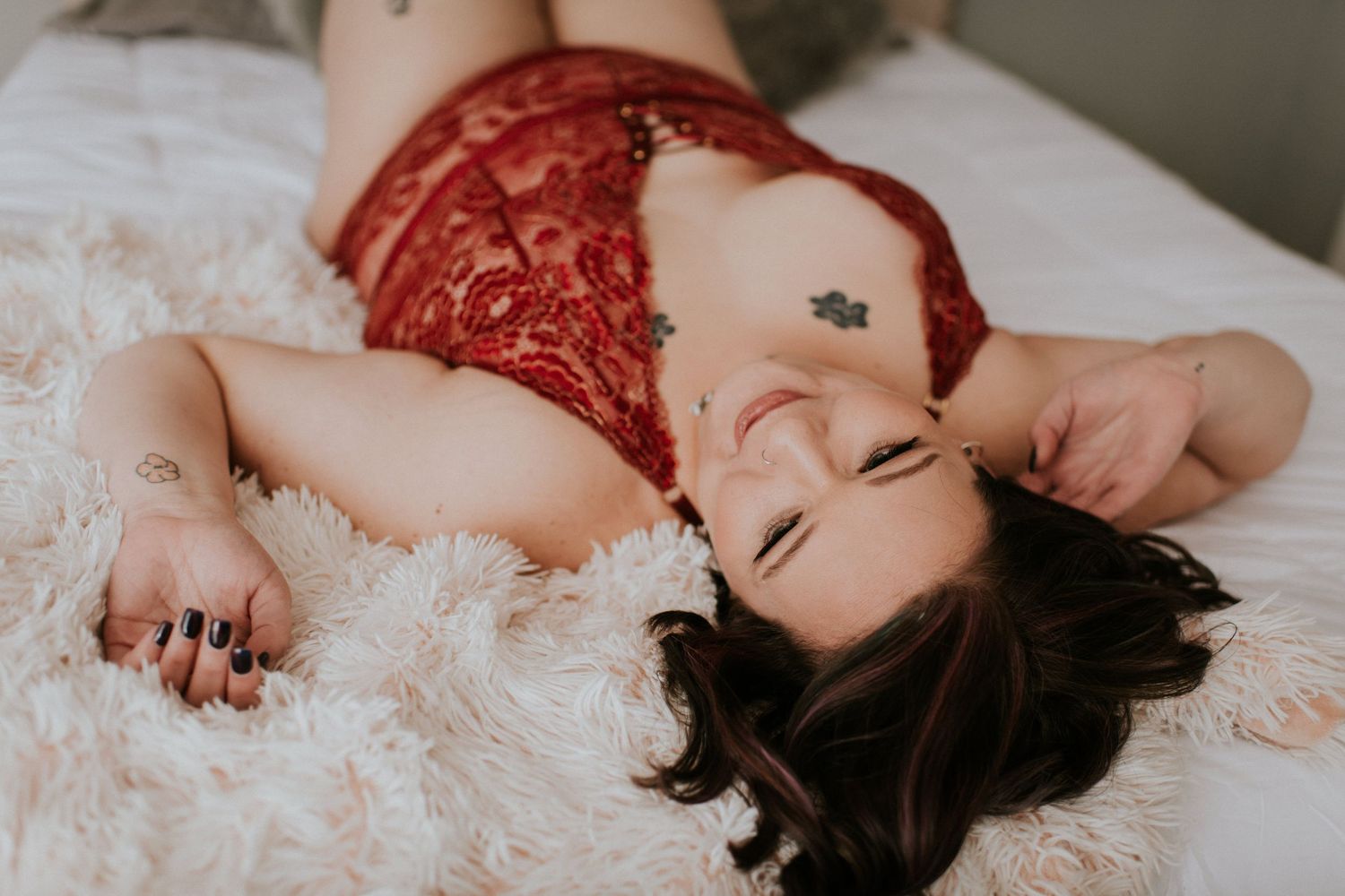 A romantic boudoir photo series showing a person with dark hair lying on white bedding in soft lighting.