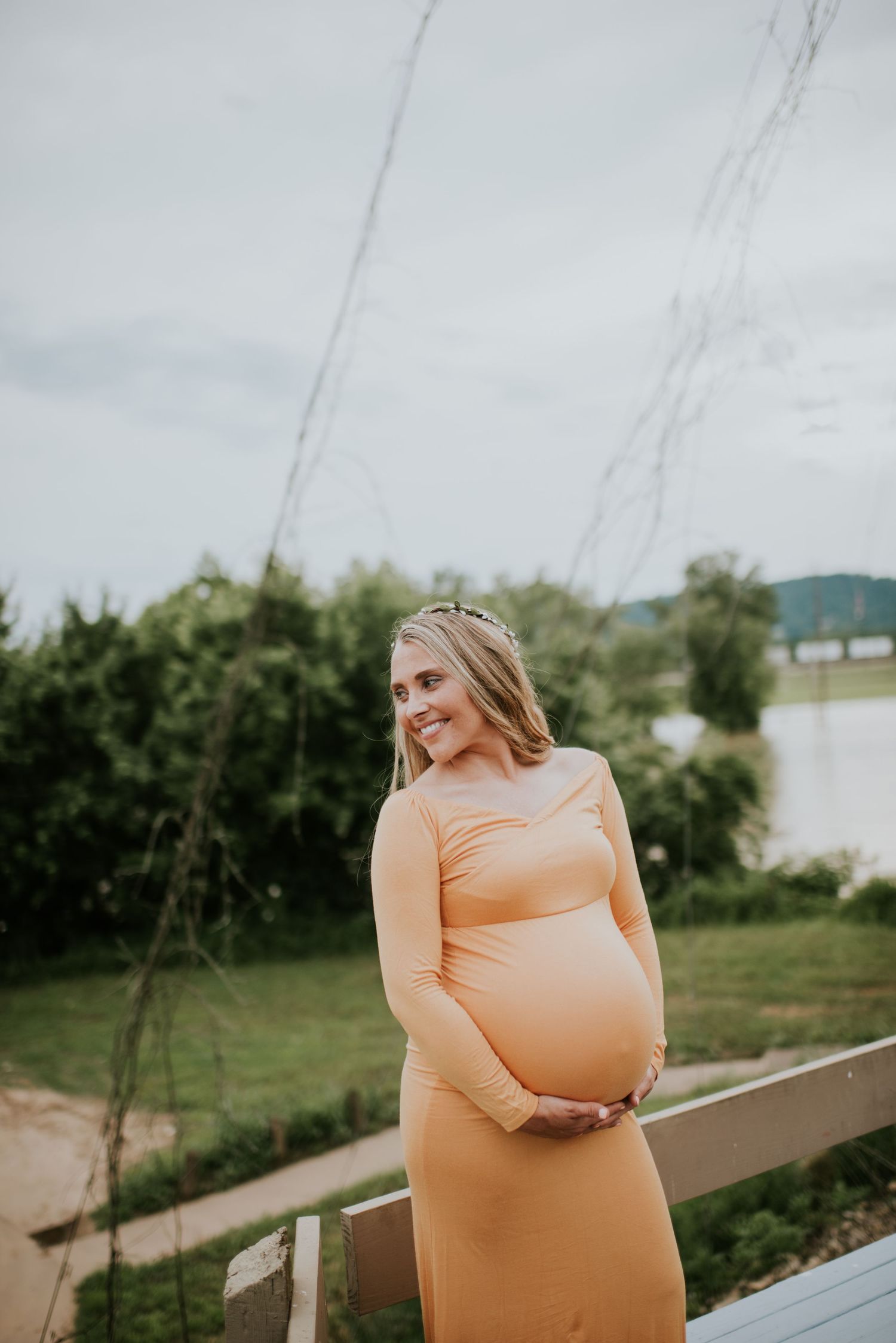 A person in a peach-colored dress stands outdoors against a scenic natural backdrop. Vanceburg Ky