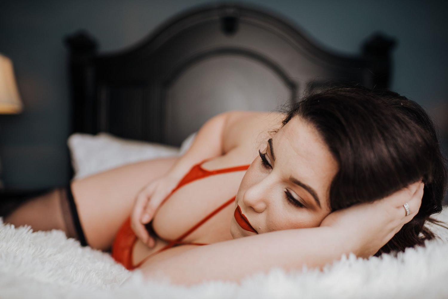 Person sleeping peacefully in bed wearing a red top against white bedding in dark lighting.