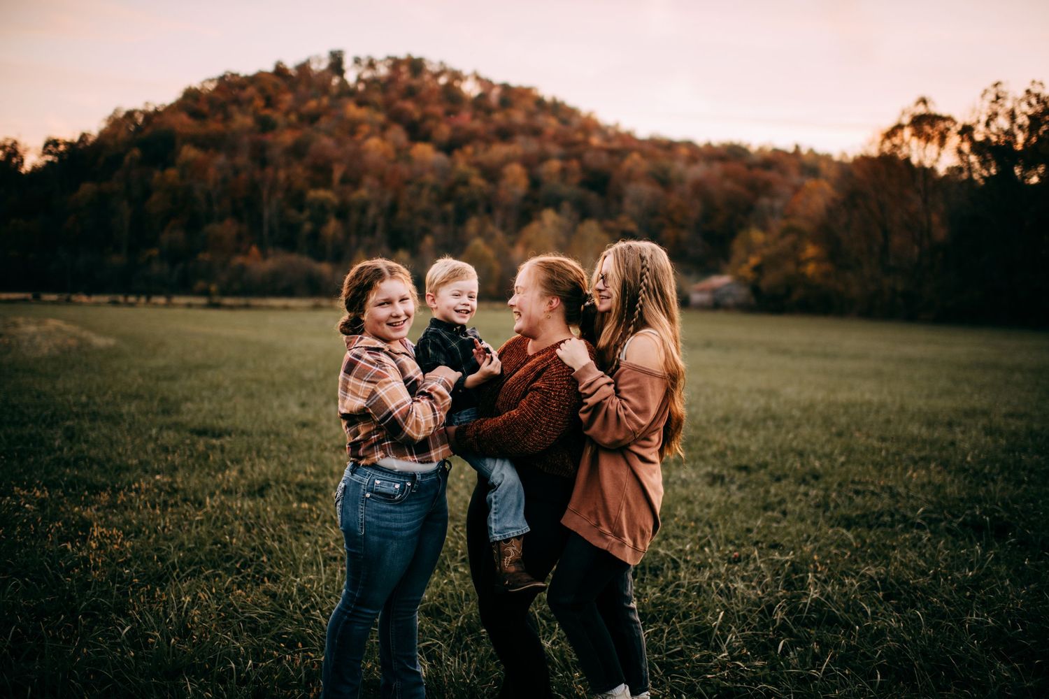 A group of people enjoying a playful moment together in a grassy field at sunset. Vanceburg Ky