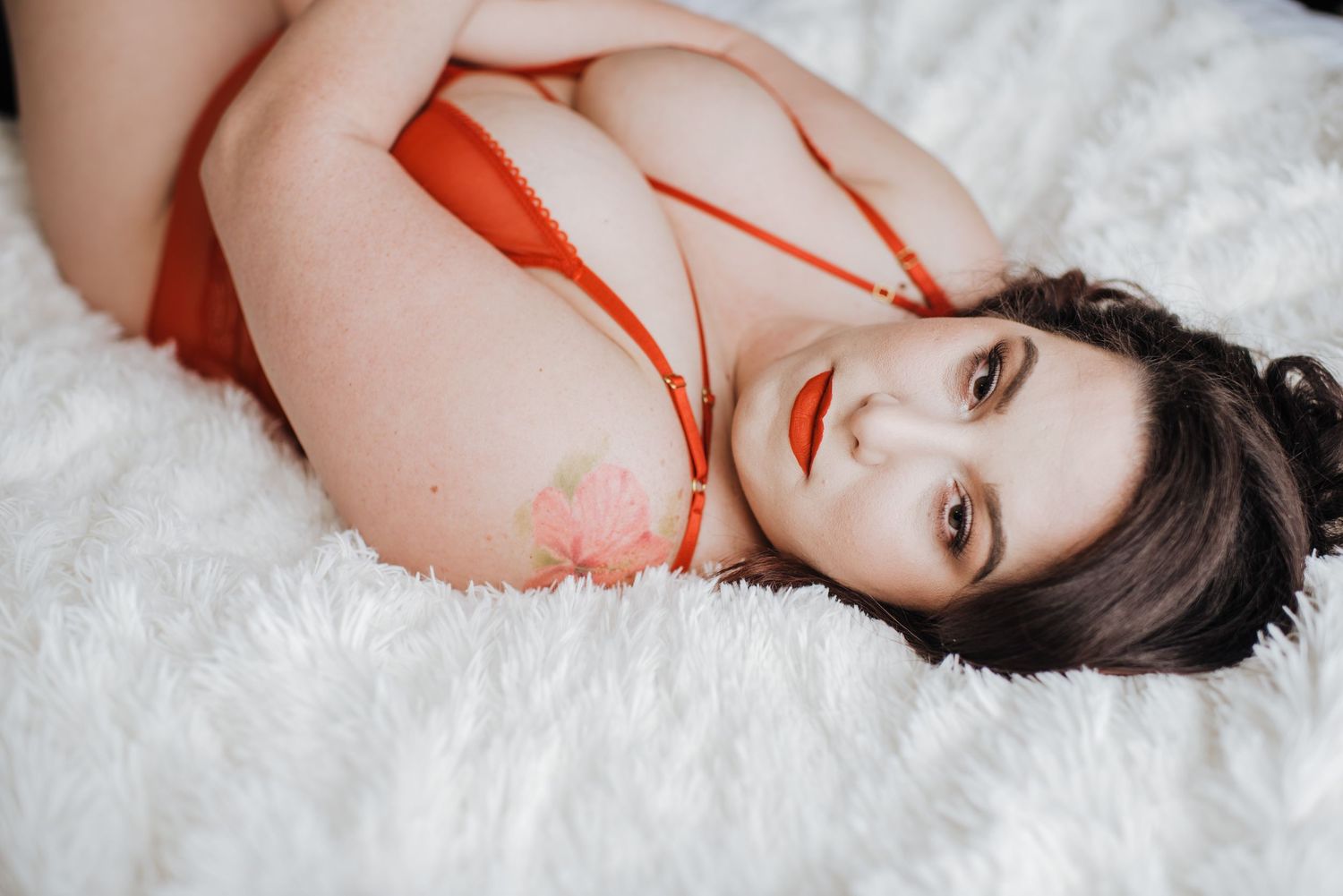 A person in a red dress lies on white fur, creating a striking contrast between colors and textures. Vanceburg Ky