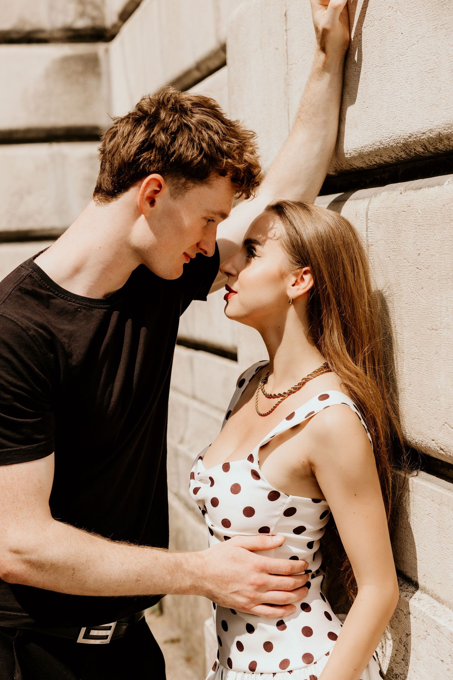 Intimate moment between couple against stone wall background.