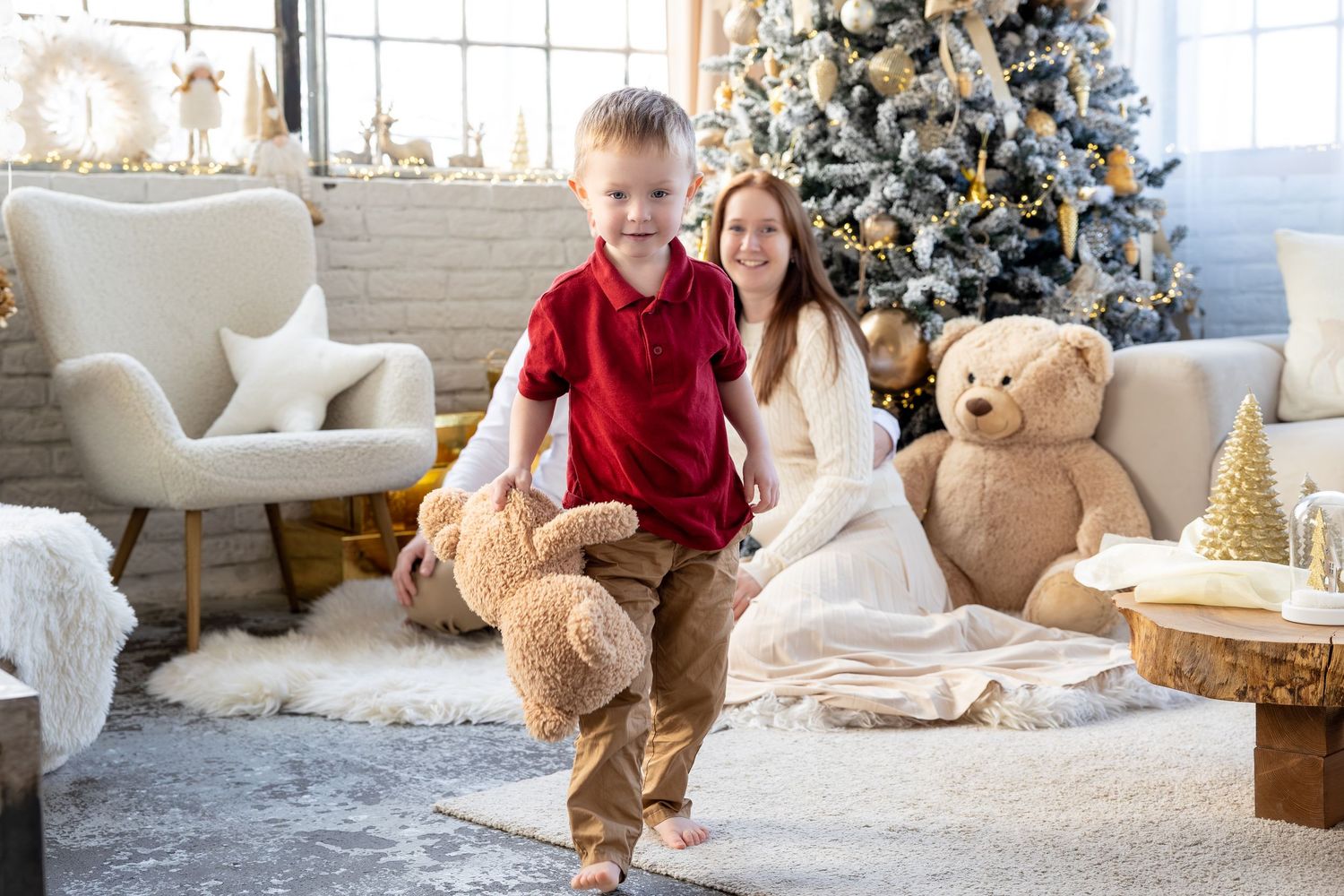 A festive holiday scene with a decorated Christmas tree, white decor, and cozy seating in a bright interior.