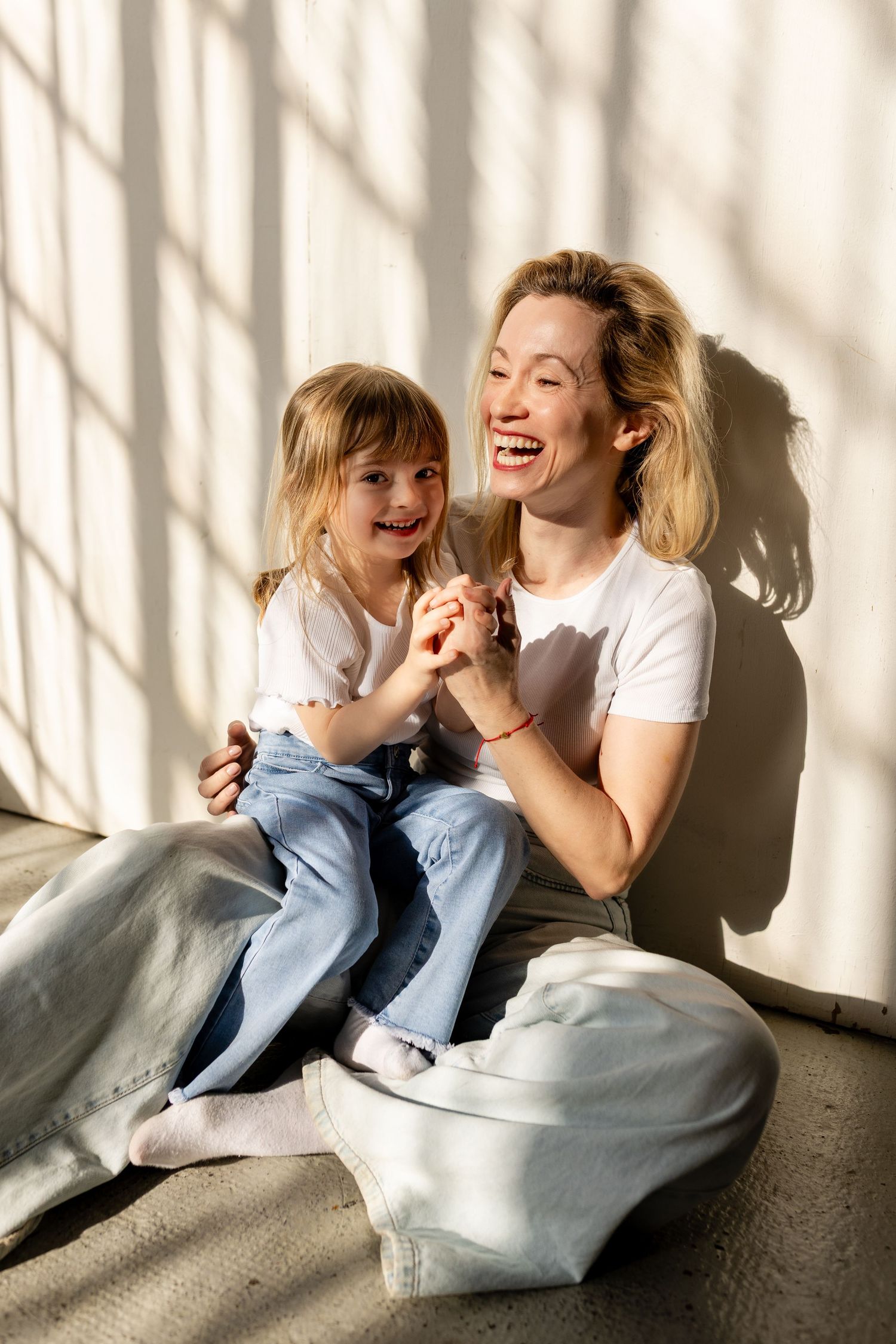 A series of four candid photos showing joyful laughter and playful moments on a sunlit floor with dramatic shadows.
