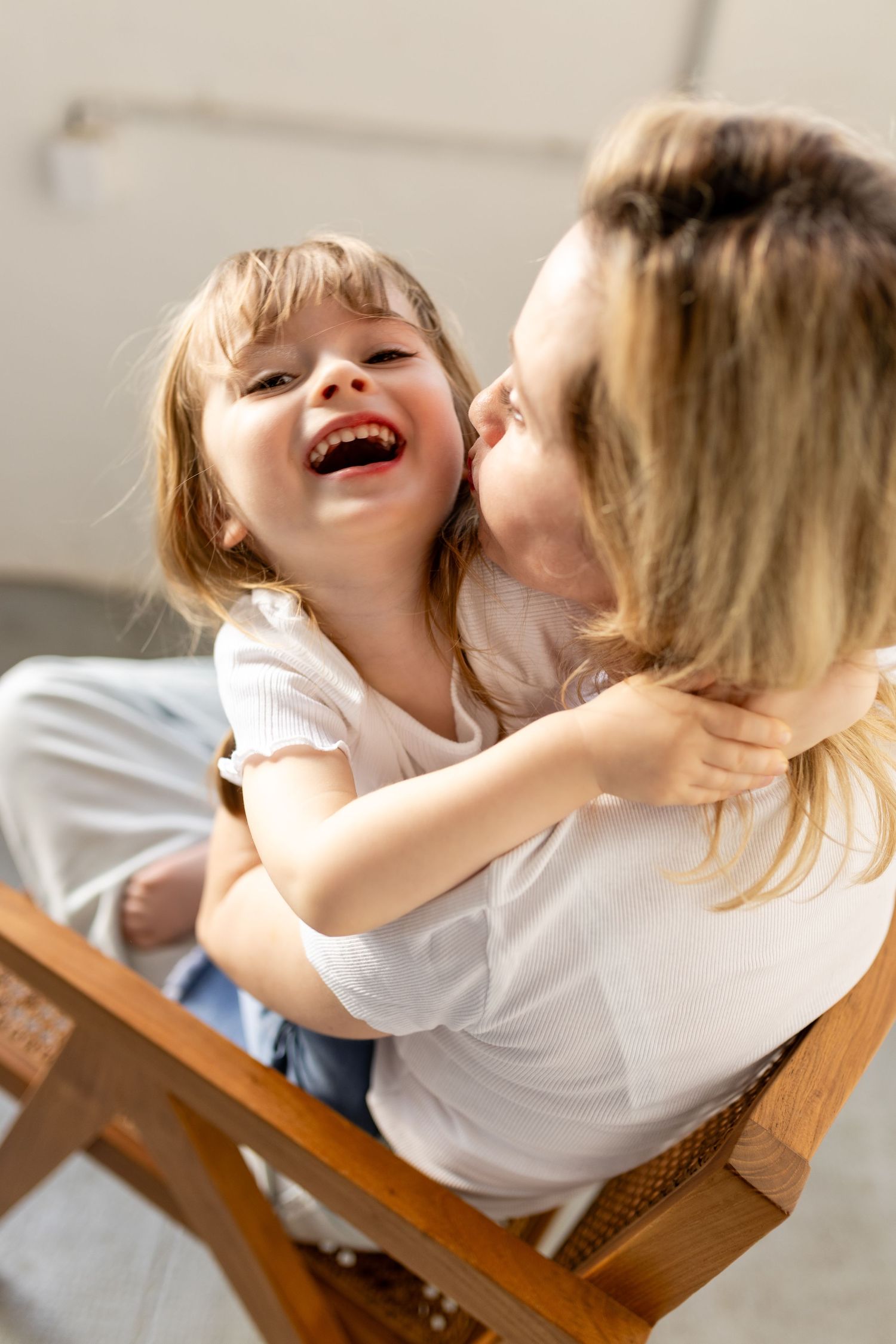 A sequence of joyful candid moments shows a child laughing and playing while sitting in a wooden chair.