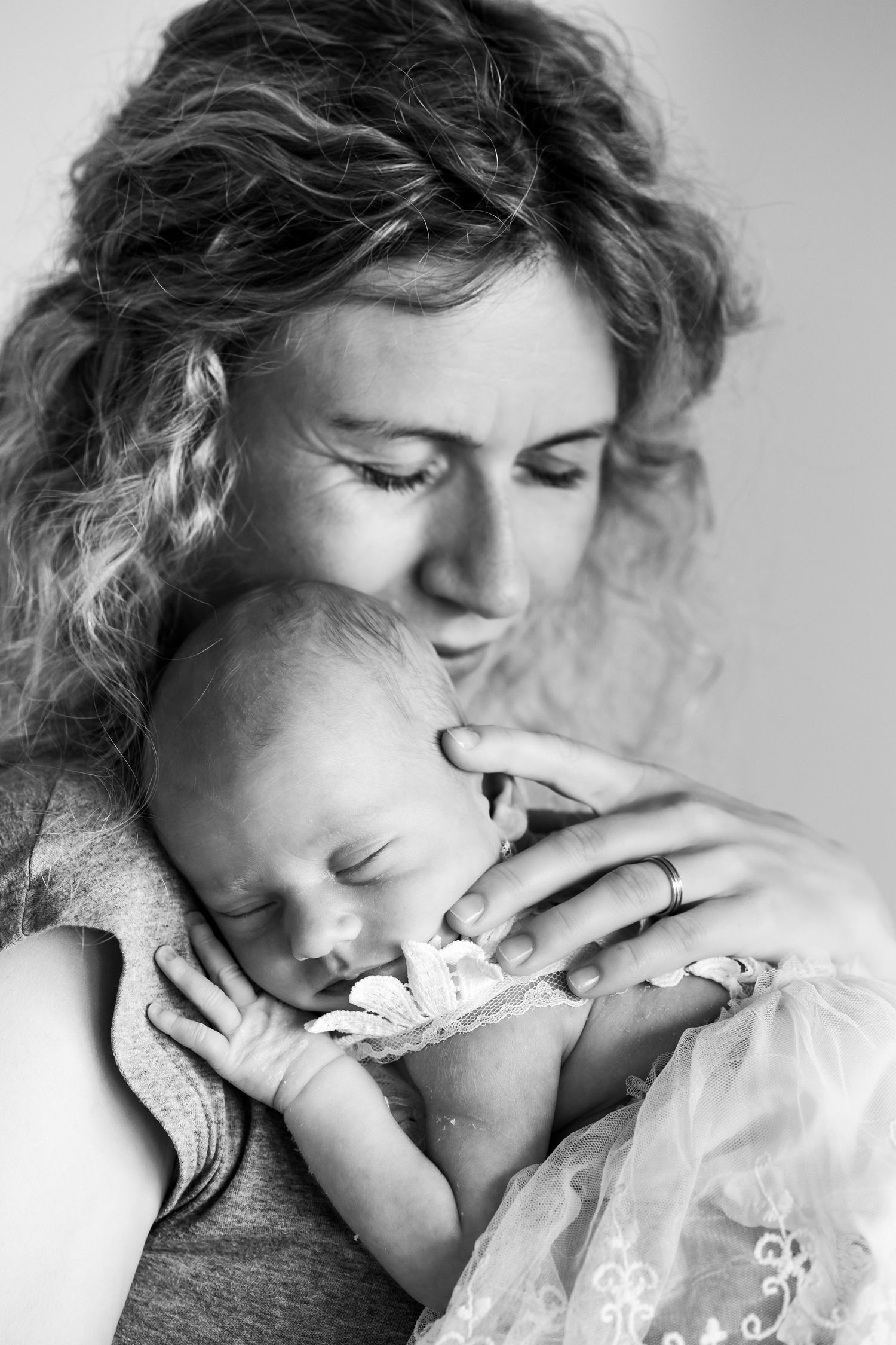 Intimate black and white portrait of parent and sleeping baby in tender embrace.