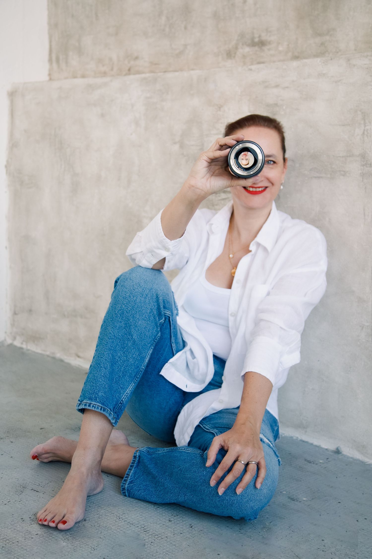 A casual portrait series showing someone in a white button-down shirt and blue jeans sitting on a concrete floor.