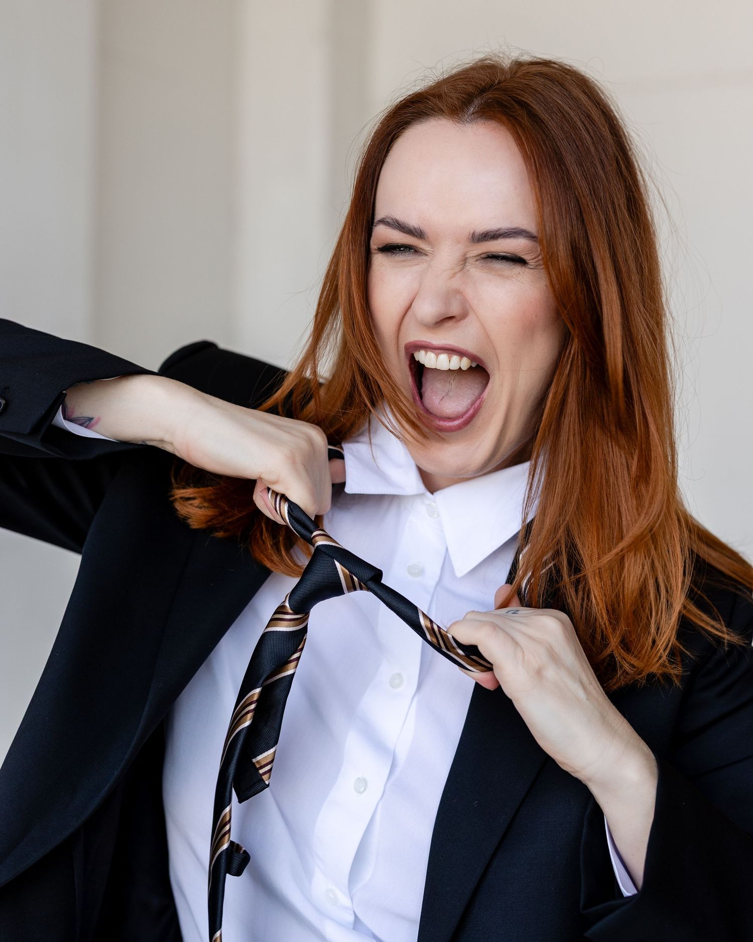 A series of photos showing someone in a black blazer and white shirt adjusting their necktie while laughing joyfully.