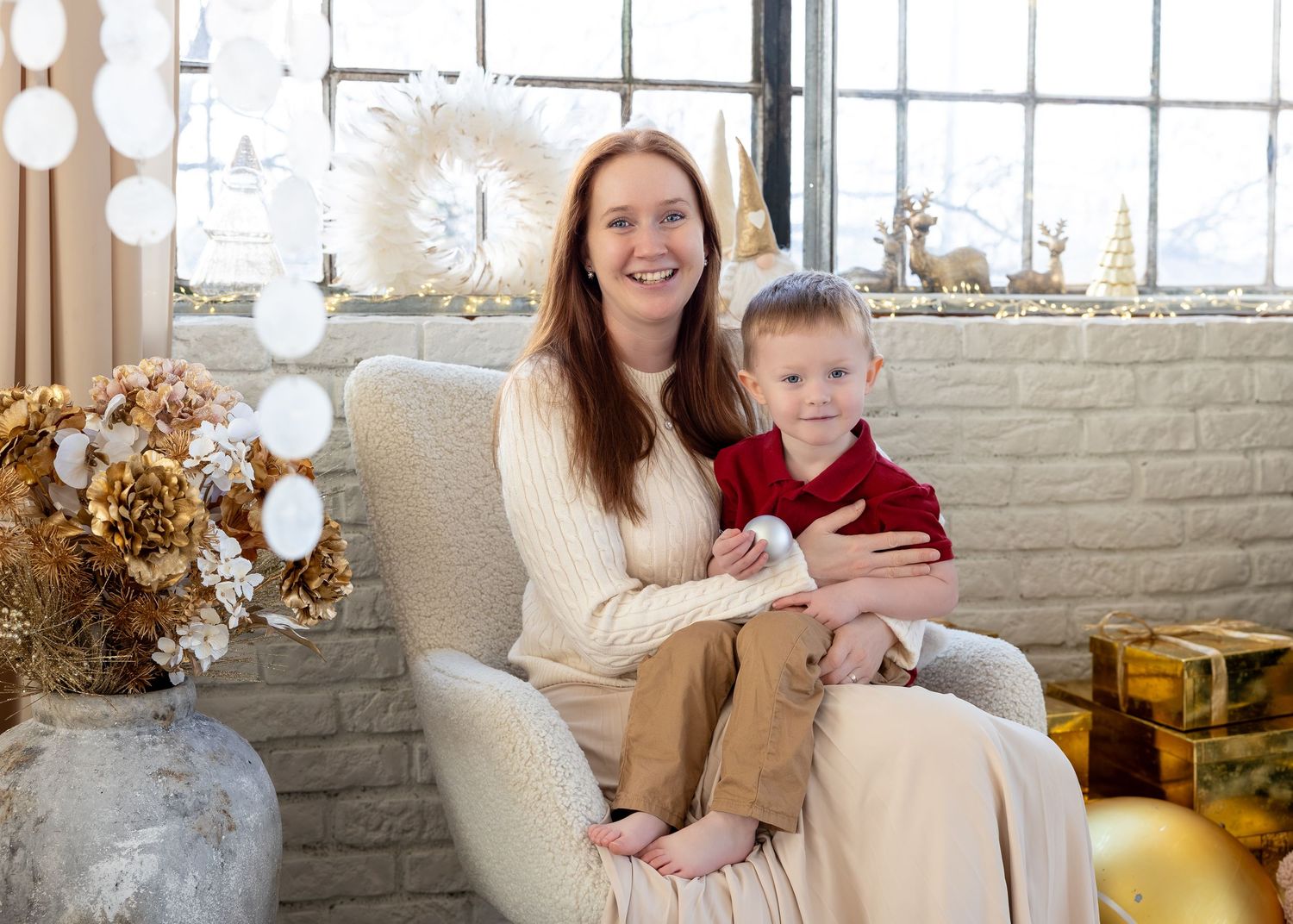 A cozy holiday scene with people sitting on a white couch in front of a decorated Christmas tree and festive decor.