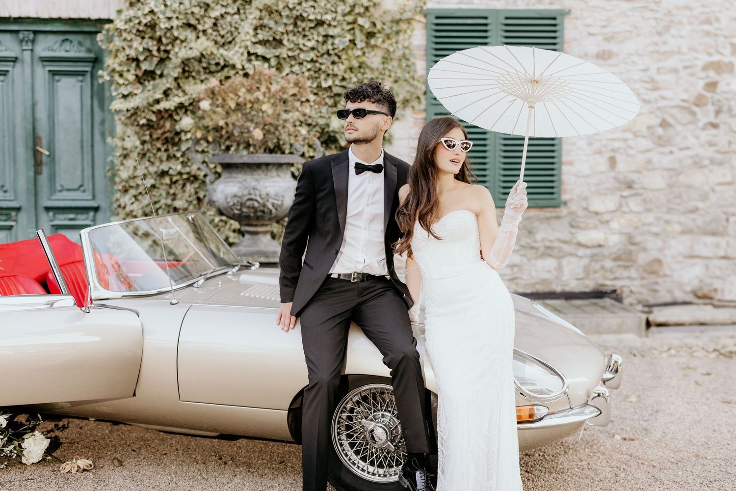 Romantic wedding photography session featuring vintage car and elegant parasol in muted tones.