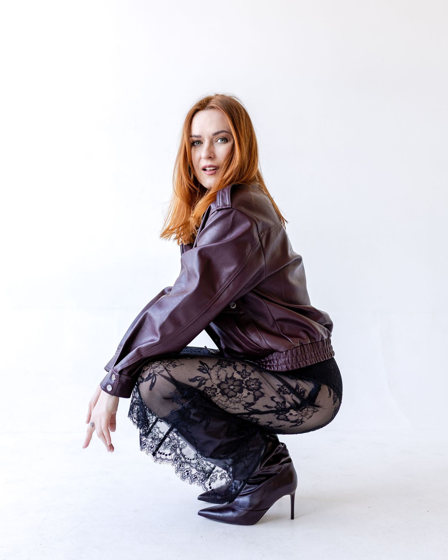 Fashion model in brown leather jacket and black lace skirt poses in dynamic sequence against white background.