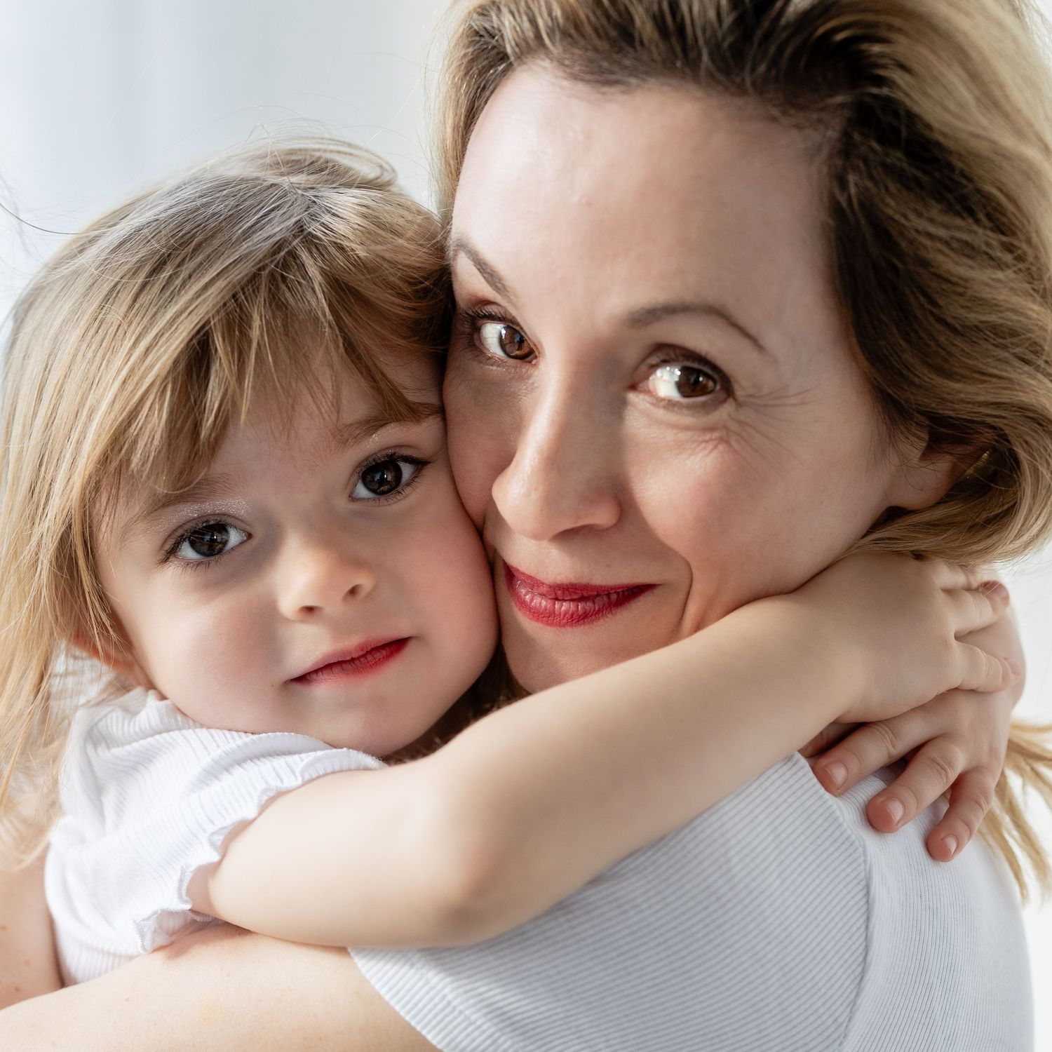 A series of intimate black and white photographs showing tender moments between parent and child against a white background.