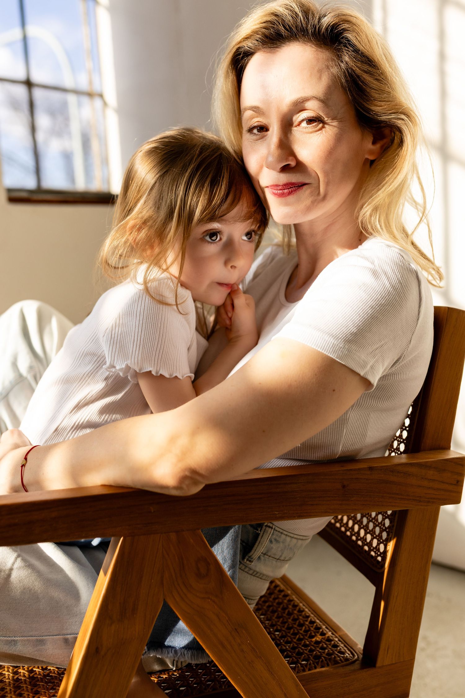 A series of four connected photos showing tender moments between a parent and child relaxing on wooden furniture in sunlight.