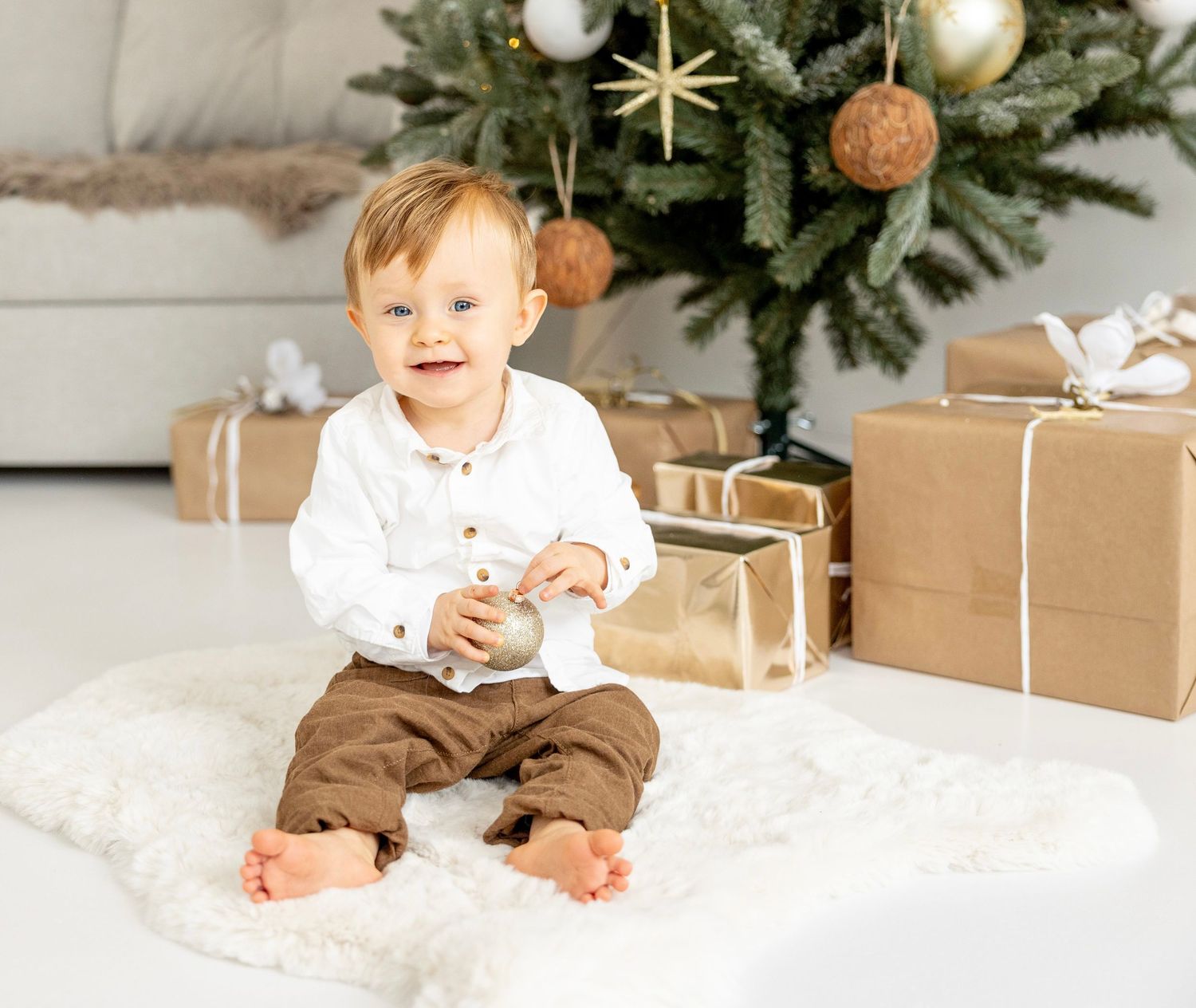 A collage of a small child in winter outfits smiling and playing with presents next to a Christmas tree.