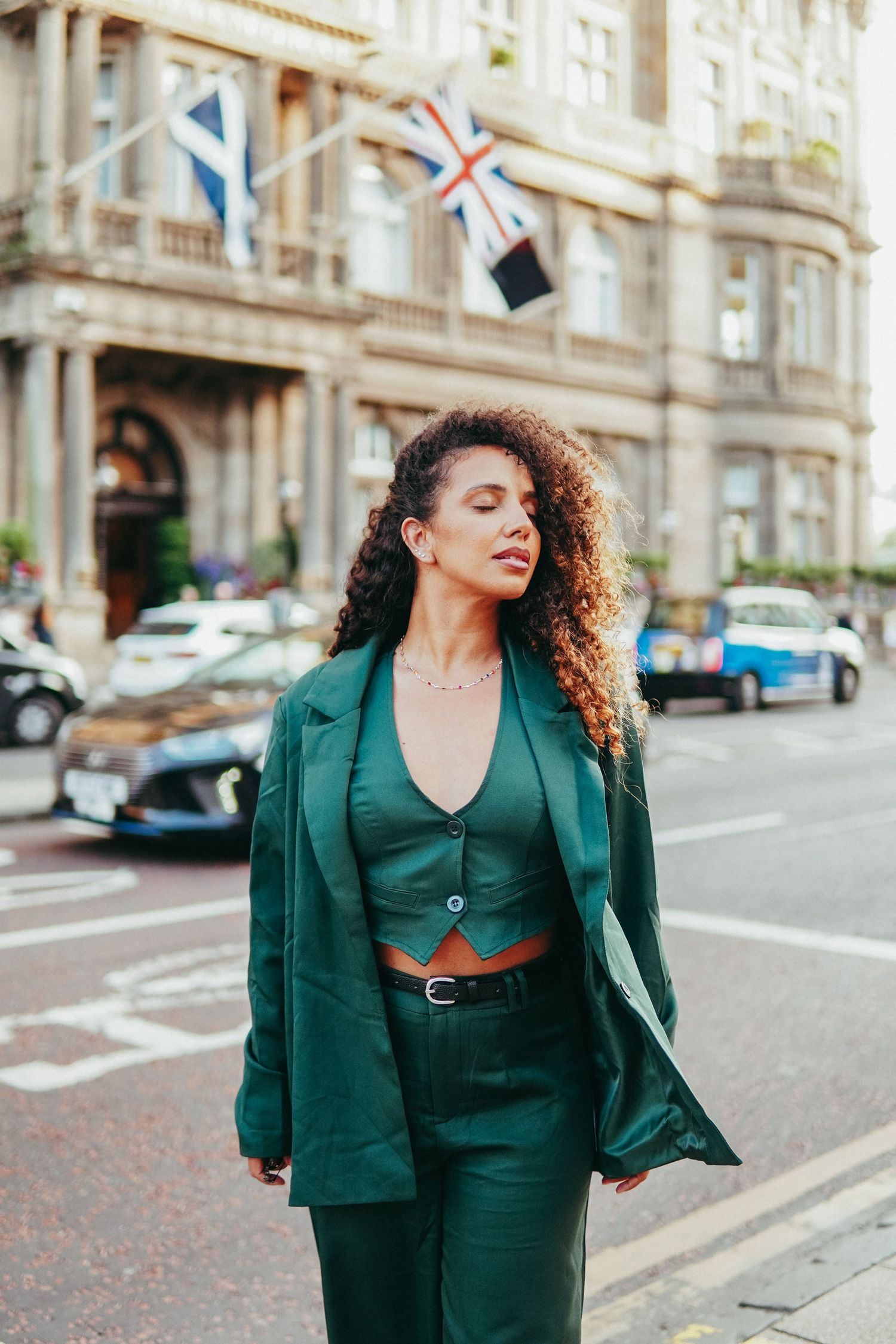 Four connected street style fashion photos featuring an emerald green power suit ensemble against an urban backdrop.