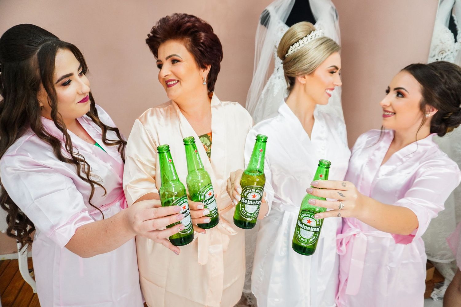 Friends in robes celebrate with green beer bottles during pre-wedding festivities.