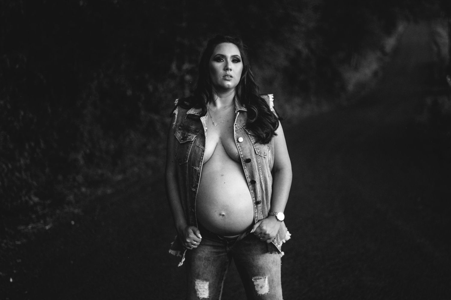 Black and white artistic maternity portrait with edgy style against dark background.