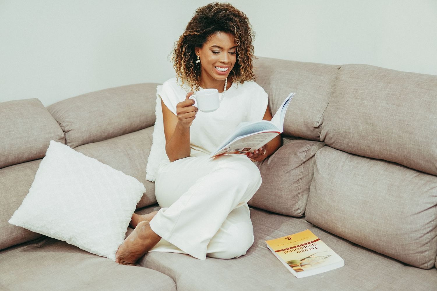 A sequence of images showing someone comfortably relaxing on a gray couch with a book.