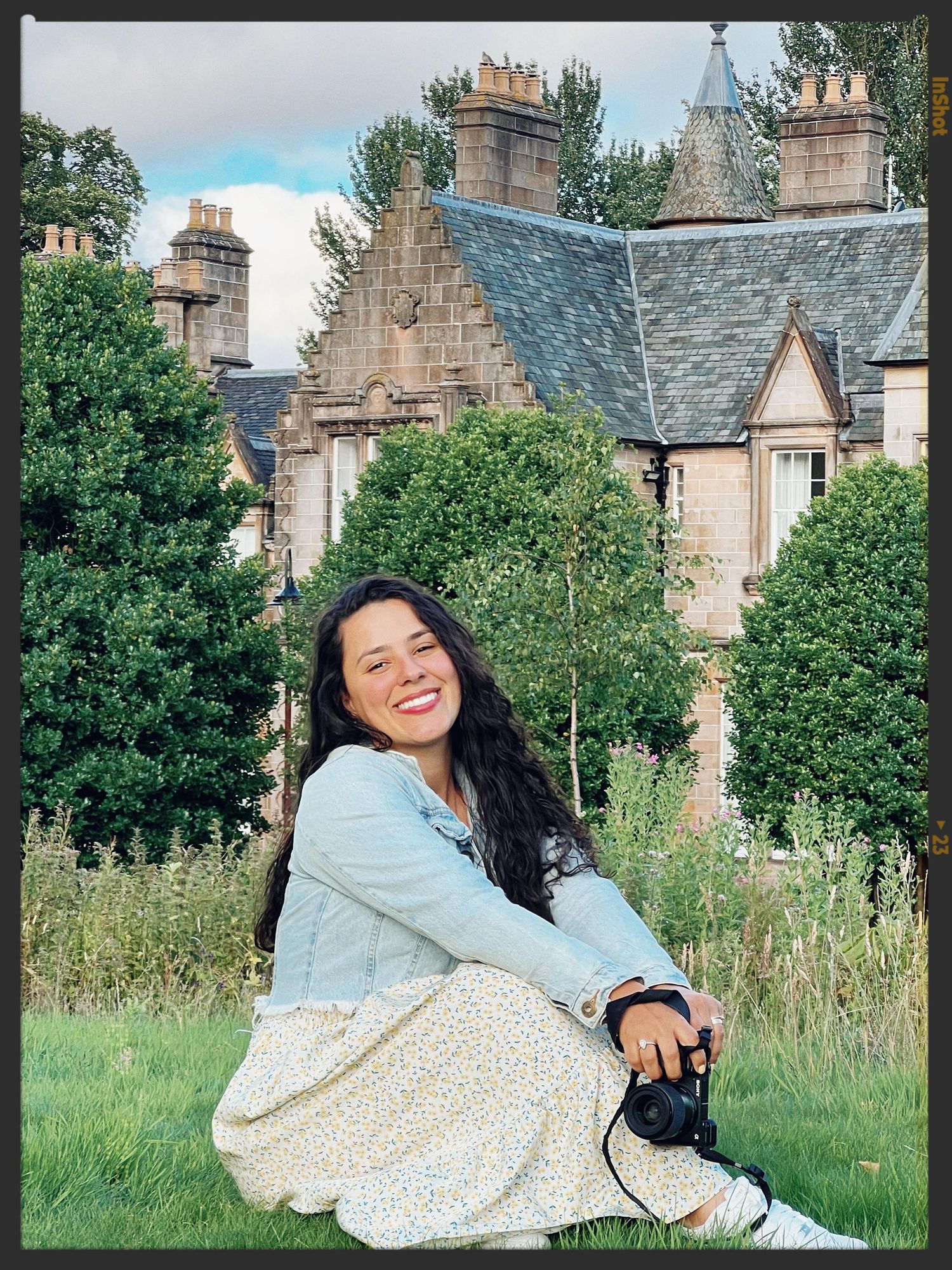 A playful portrait session in a garden with historic buildings and greenery in the background.