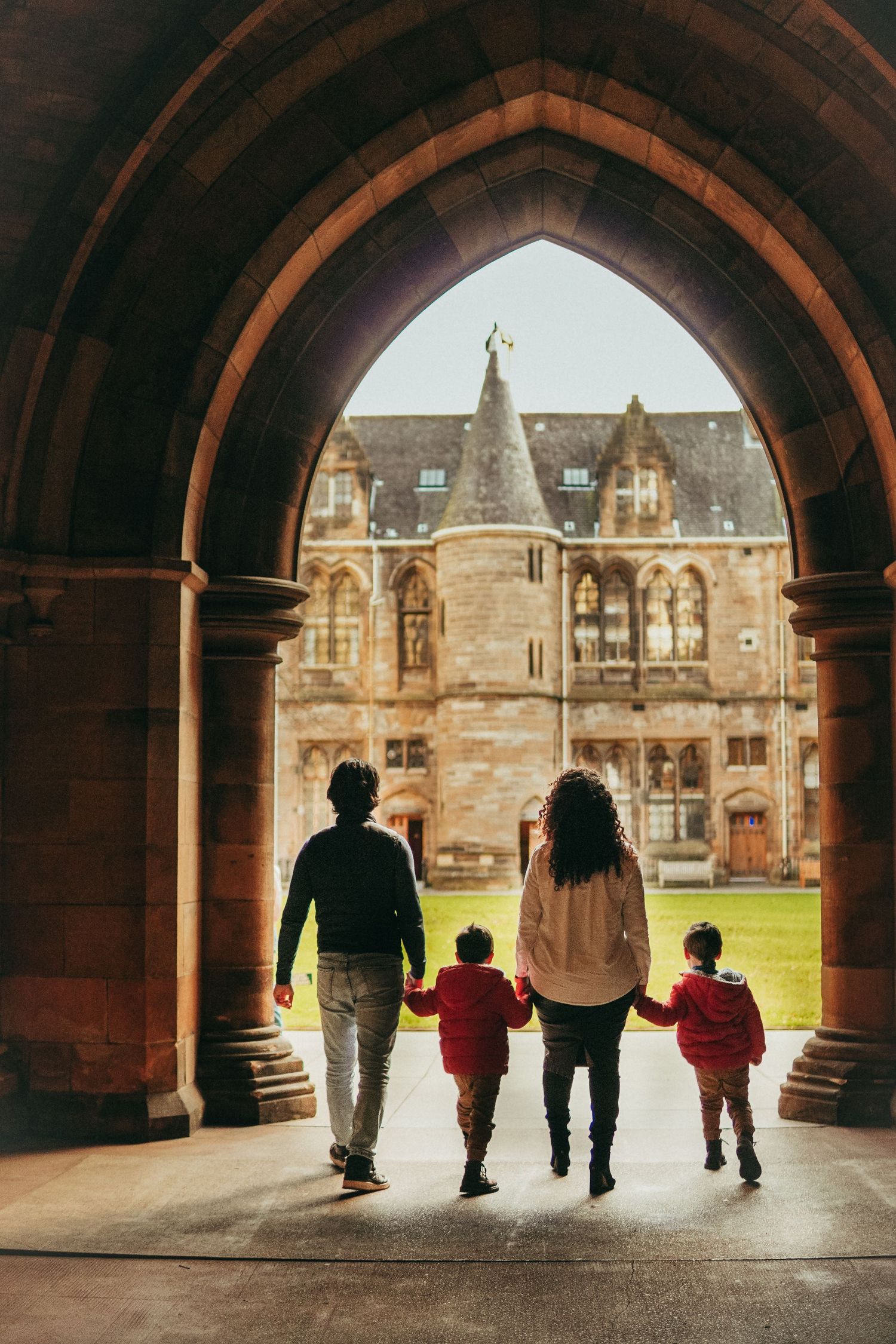 Silhouettes of a family walking together through a stone archway at a historic university building.