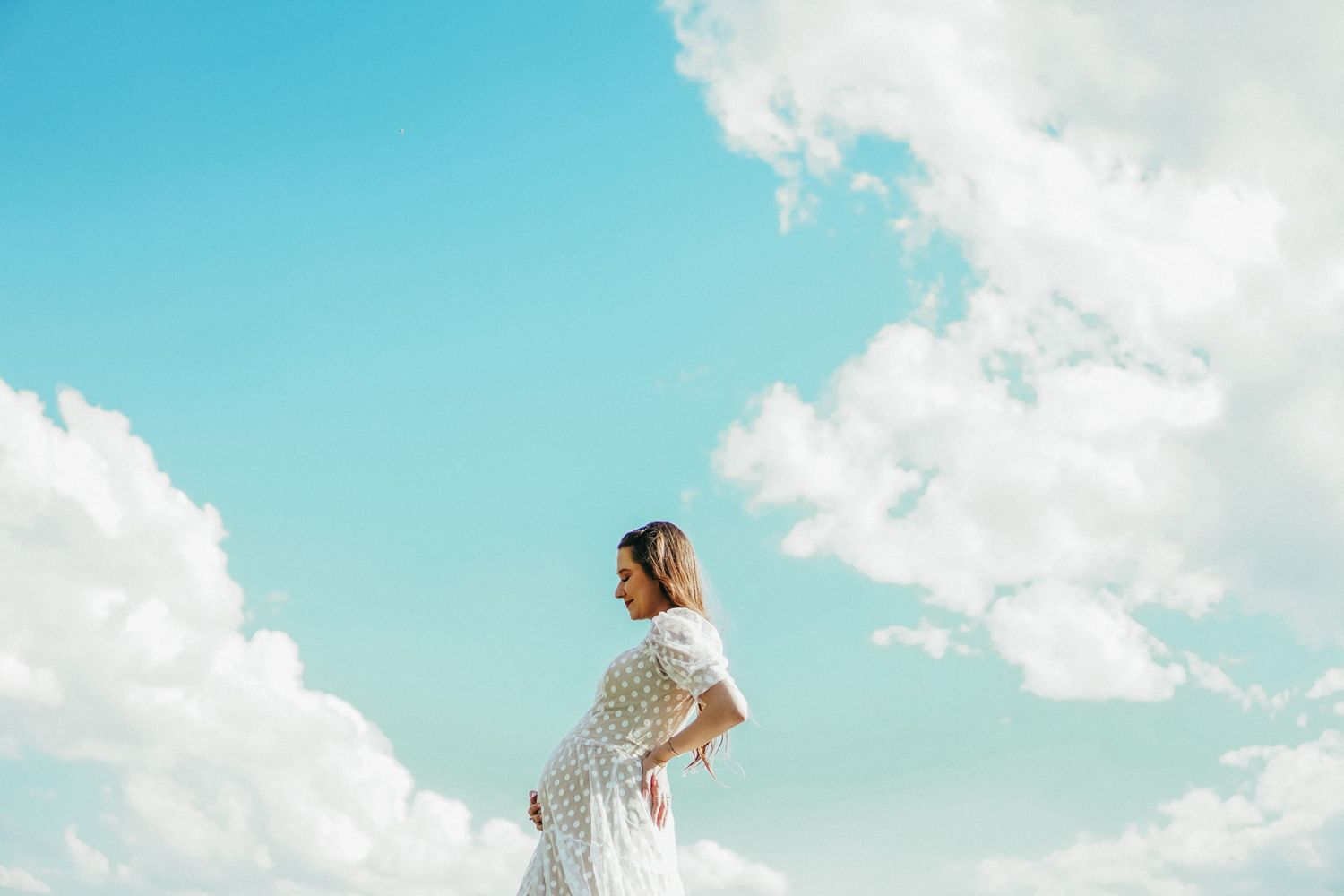 Ethereal wedding photos with bright blue skies and fluffy white clouds as backdrop.