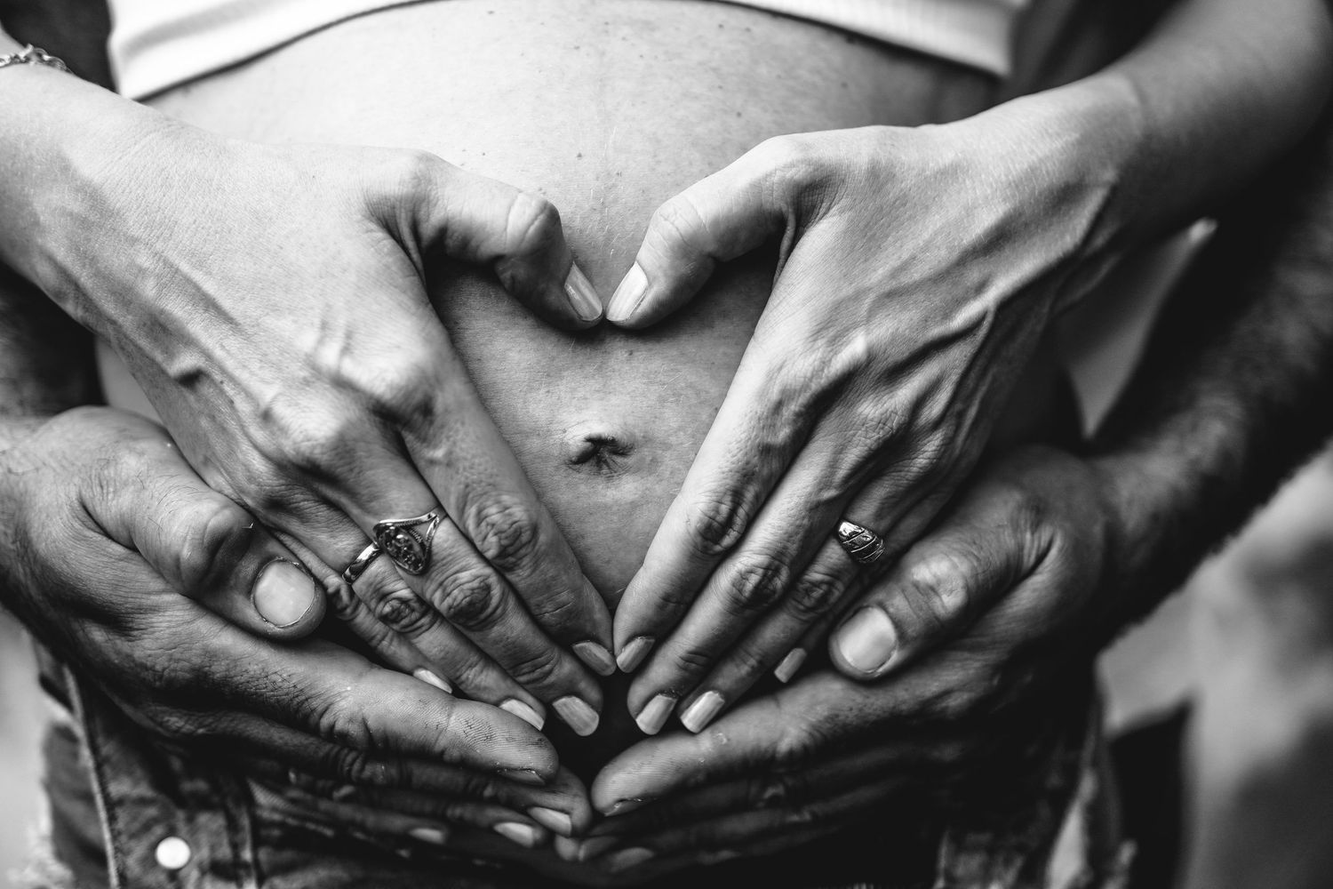 Black and white close-up shots of hands with rings showing pregnancy progression.