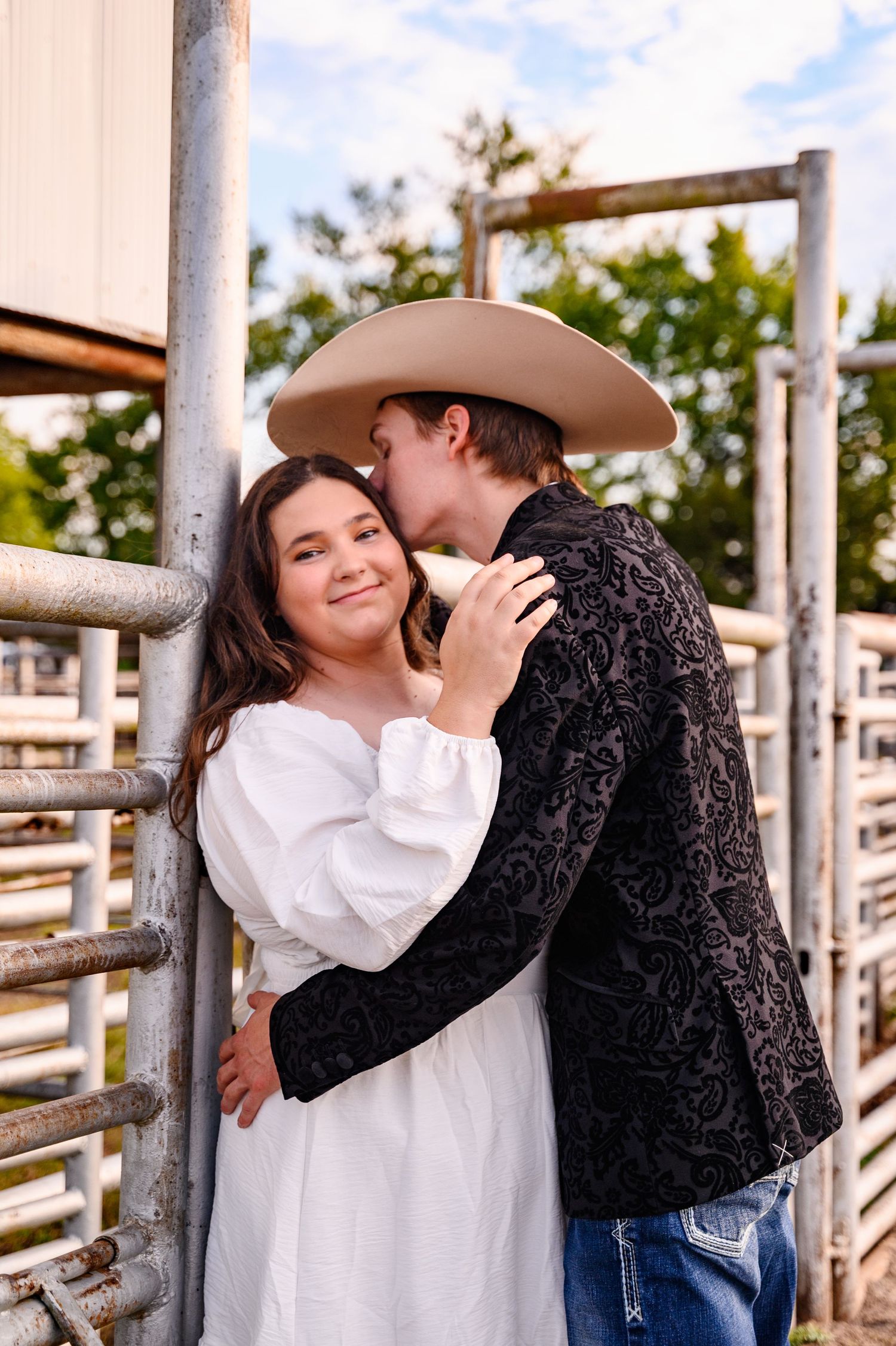 A couple shares tender moments against white fence panels at a rodeo arena in Southeast Kansas.
