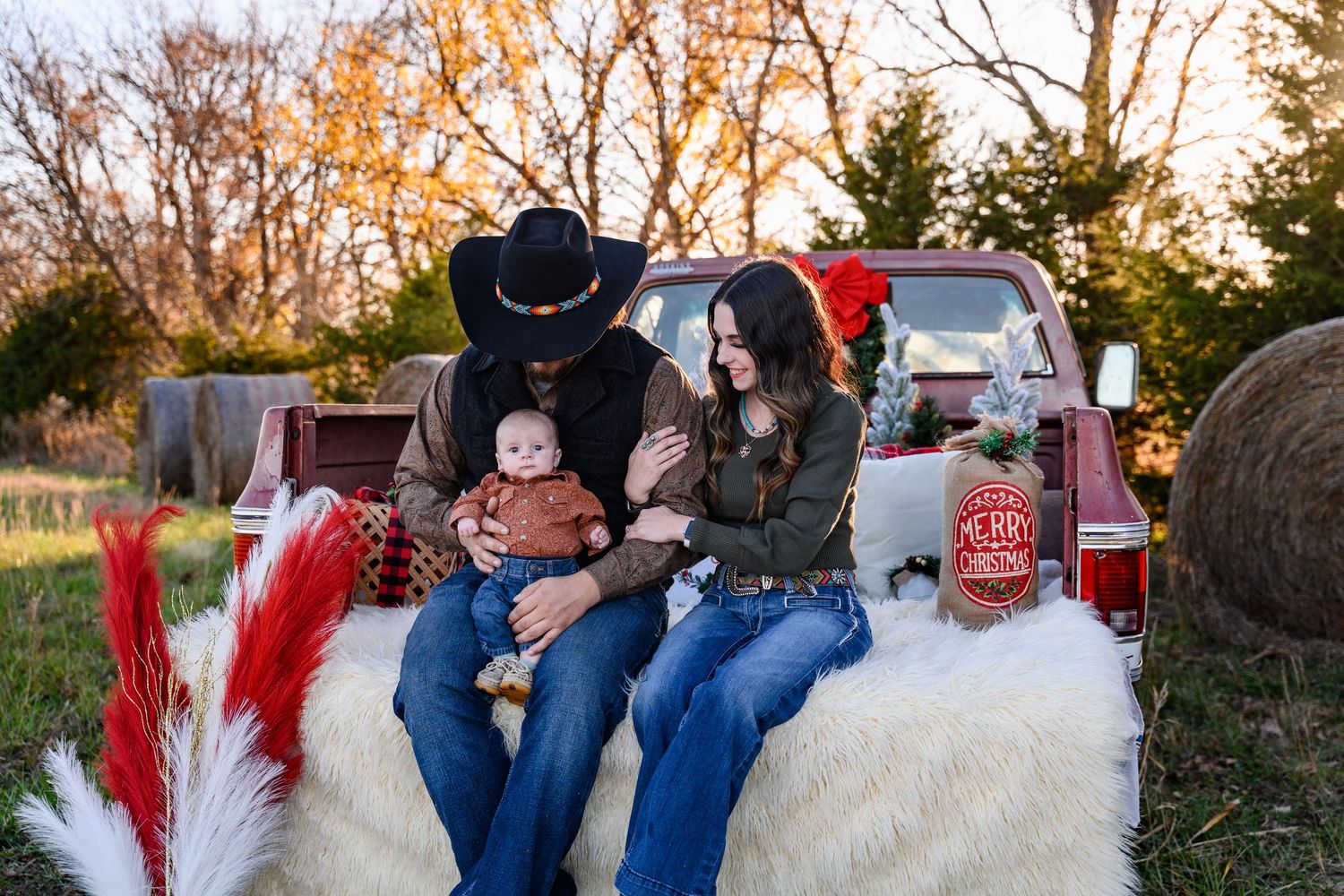A small family posing for Rustic Truck Bed Christmas Minis in Bartlett, KS.