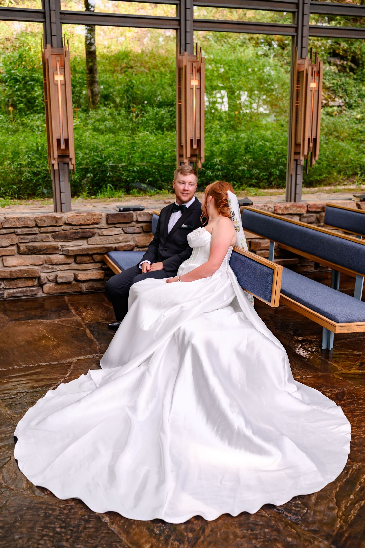 A bride and groom sitting together on a bench in a chapel, enjoying the moment after their ceremony.