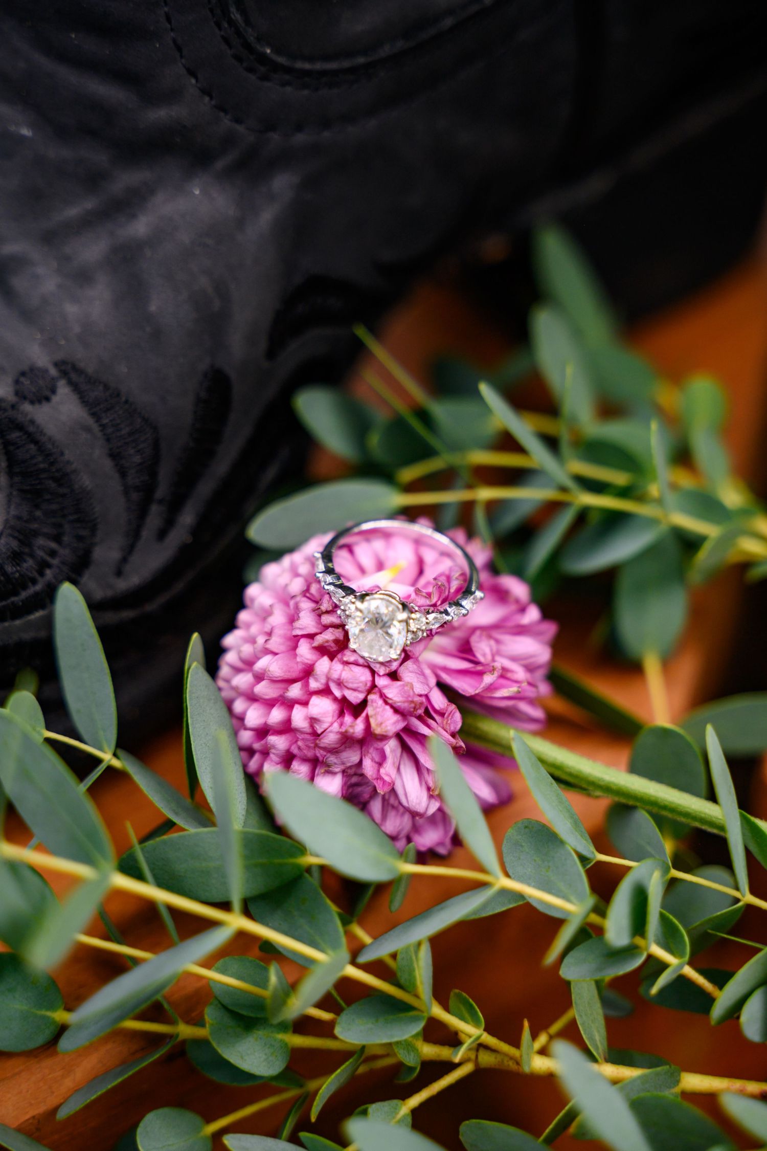 A bride's shoes, ring, and bouquet flowers arranged for a close of detail photo of the wedding ring.