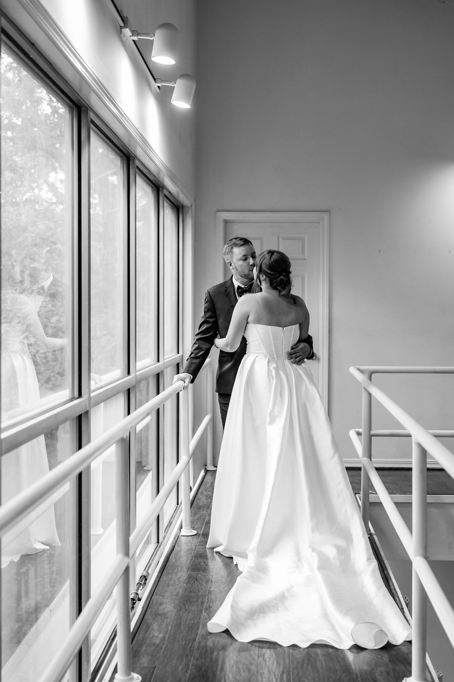 A first look with a bride and groom on a balcony next to lots of windows, with lots of lot, captured in Arkansas.