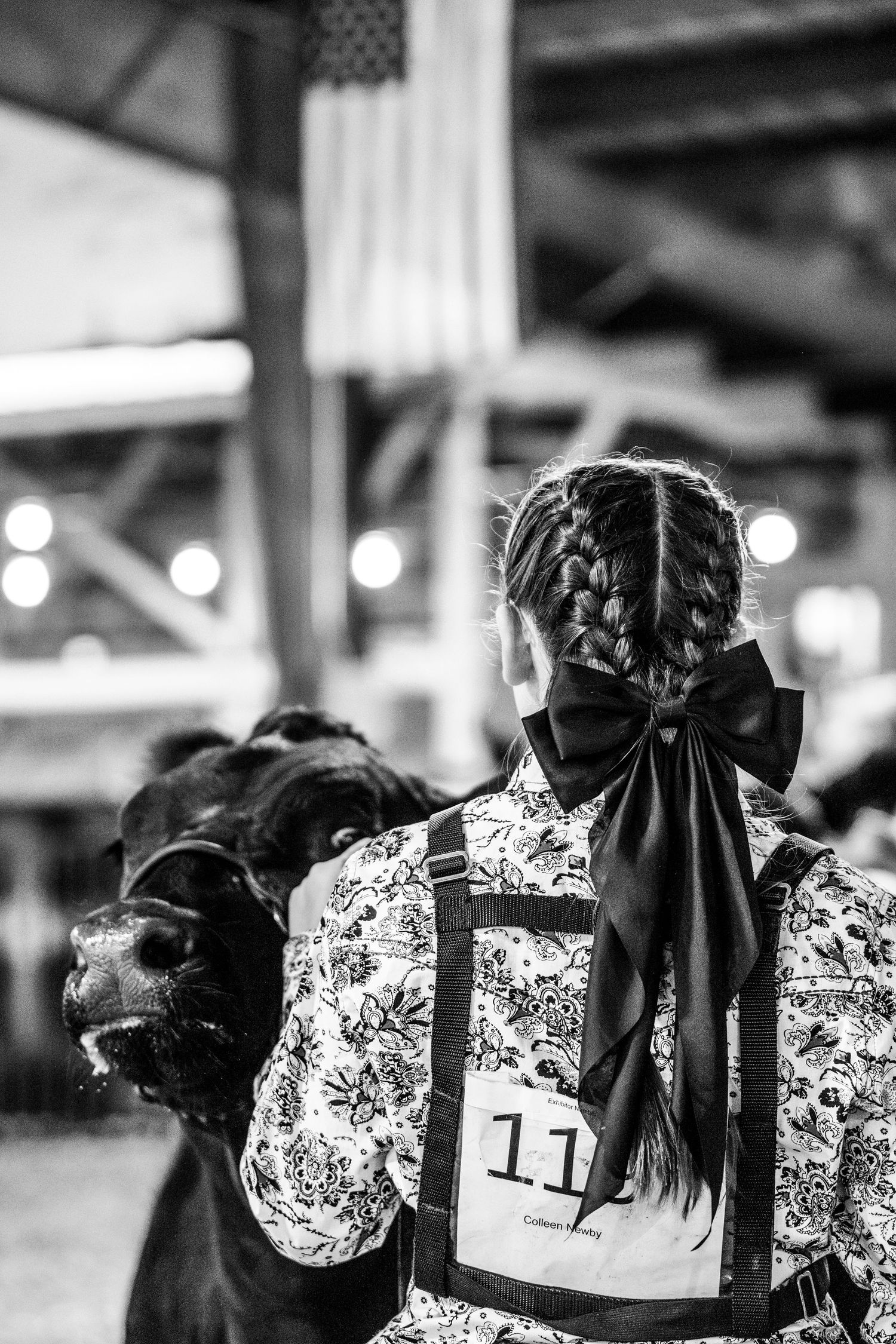 Detail shot of a girl wearing a black bow and a floral shirt, while showing her heifer at the Labette County Fair.
