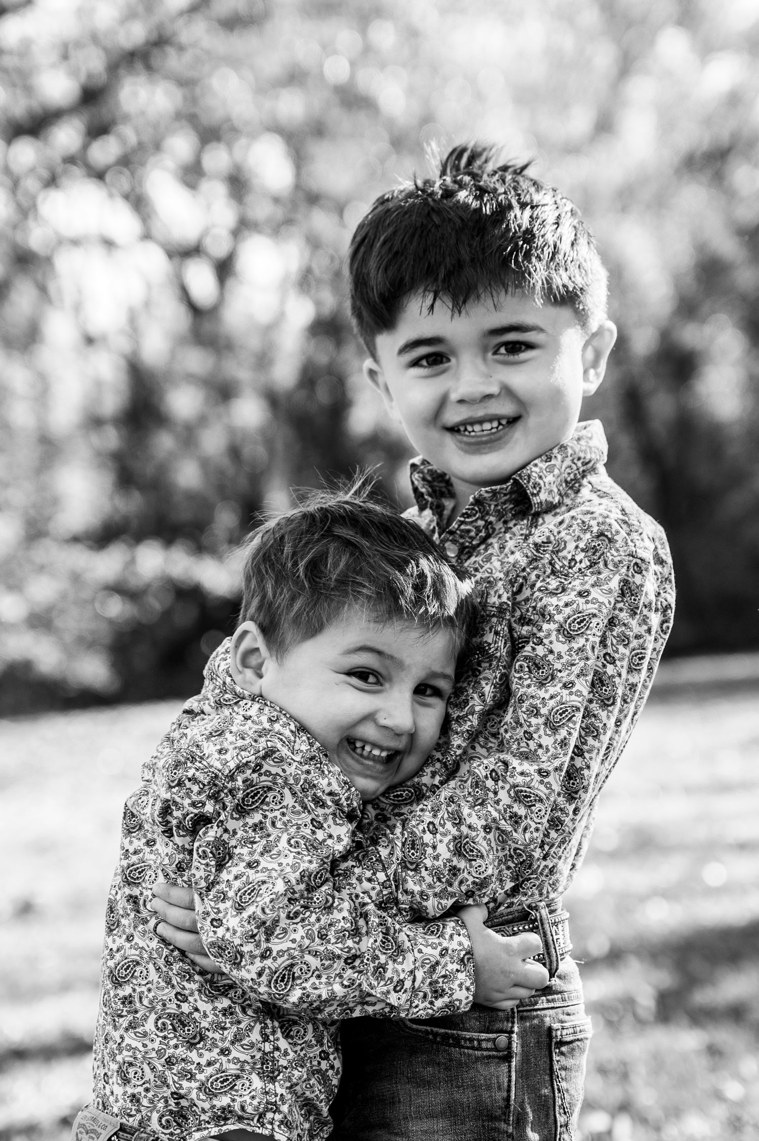 Two brothers hugging each other and smiling at the camera.