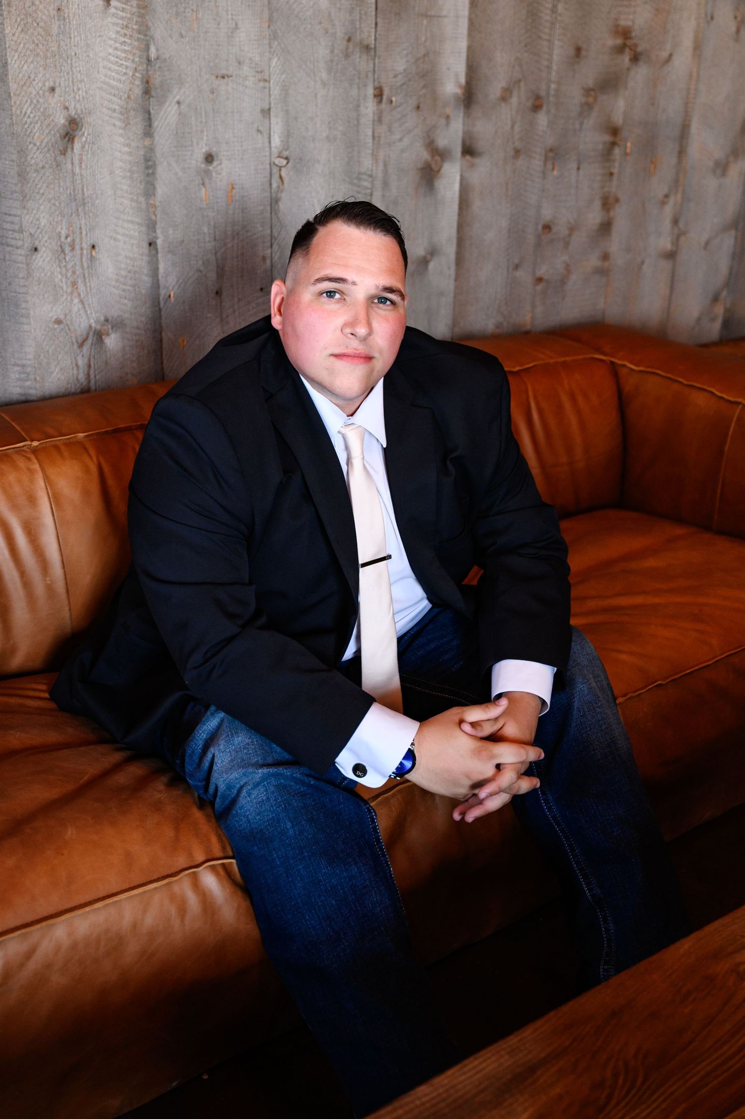 A groom sitting on a leather couch before his wedding ceremony.