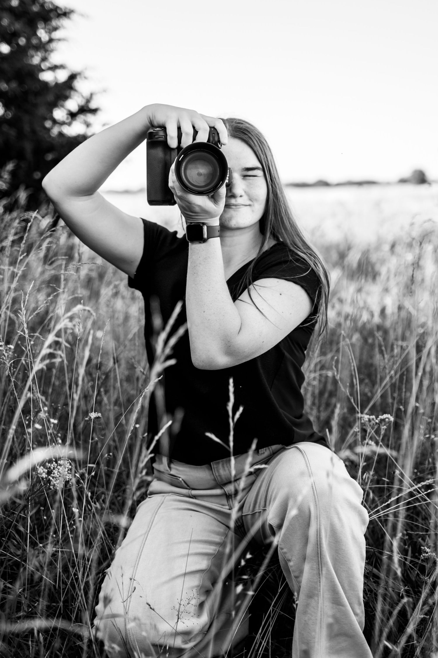 Amber Ross- photographer, sitting in a grassy field in Bartlett, KS