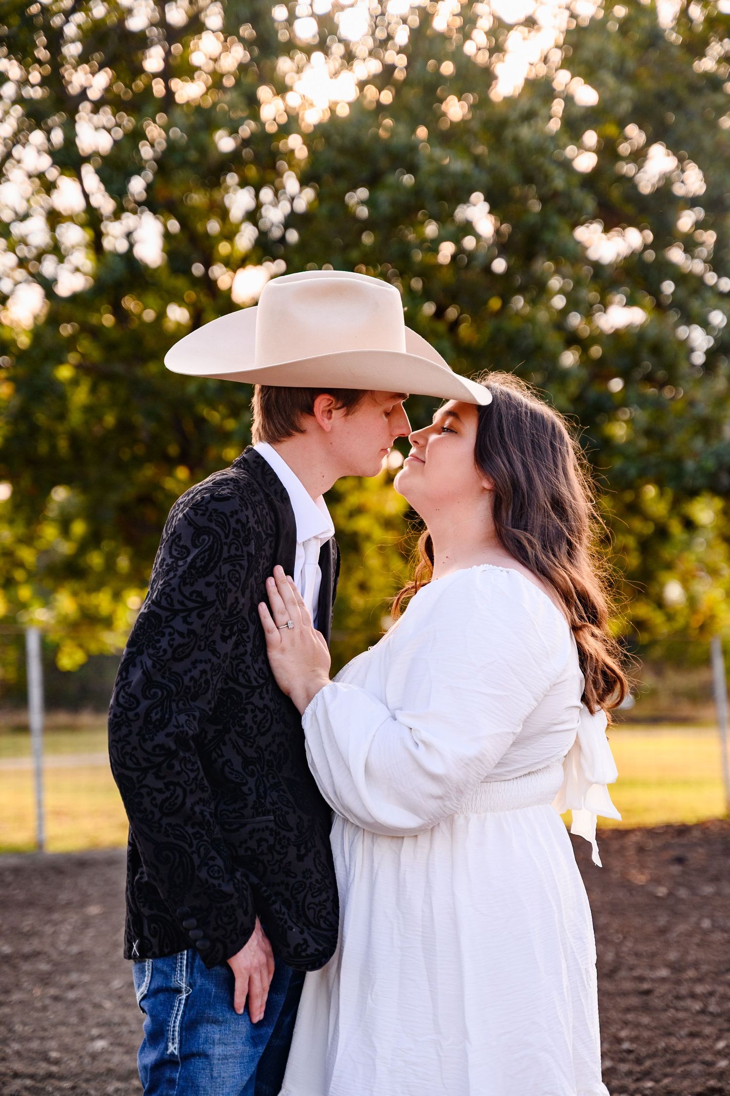 A Kansas couple shares a kiss during their engagement session at sunset at the rodeo grounds.