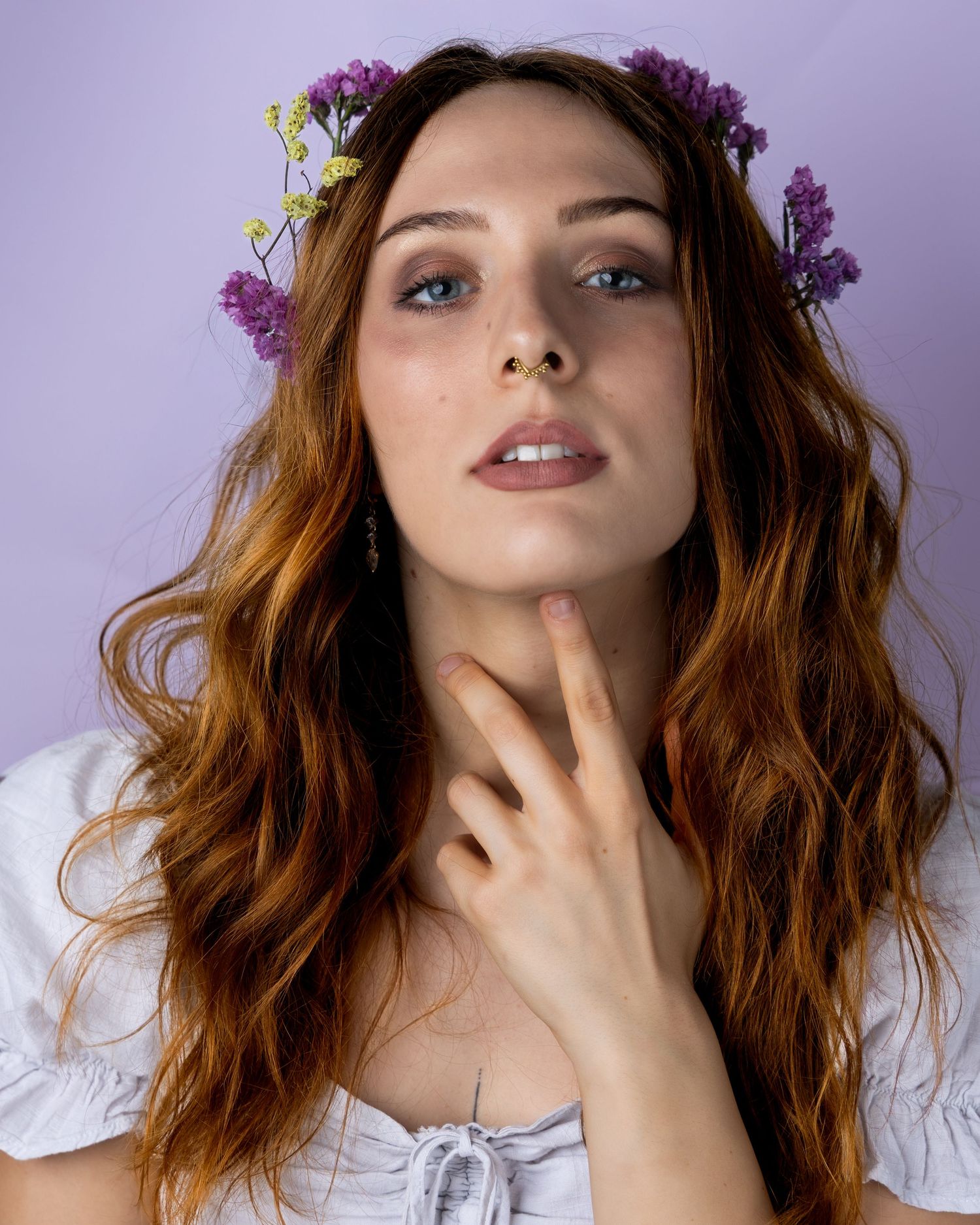 A person wearing a purple flower crown poses expressively against a light background in a series of artistic portraits.