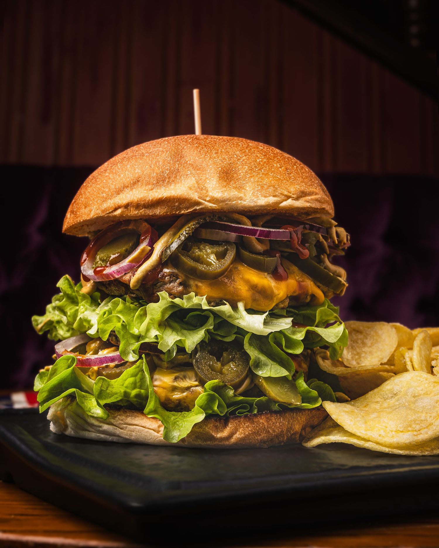 Classic cheeseburger on a toasted bun with fresh lettuce, tomato, and melted cheese served on a dark plate.