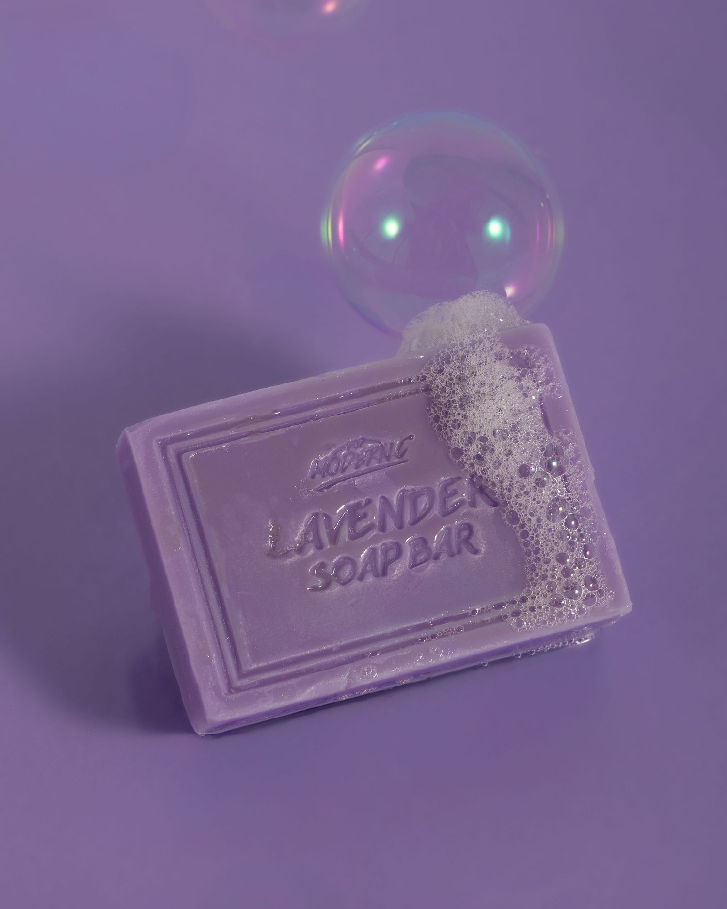 A lavender soap bar with bubbles floating above it in a dreamy purple-tinted artistic composition.