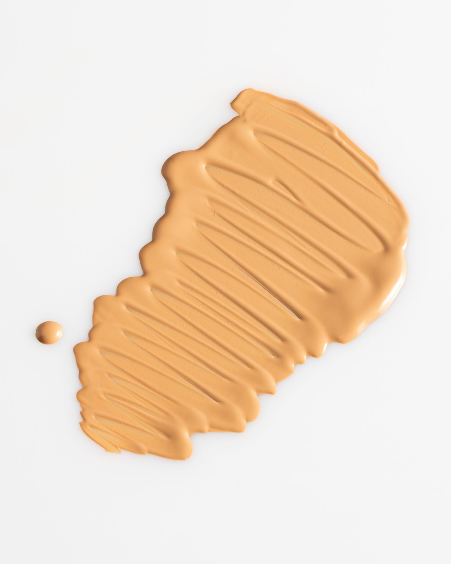 A smeared beige liquid foundation or concealer makeup sample on a white background.