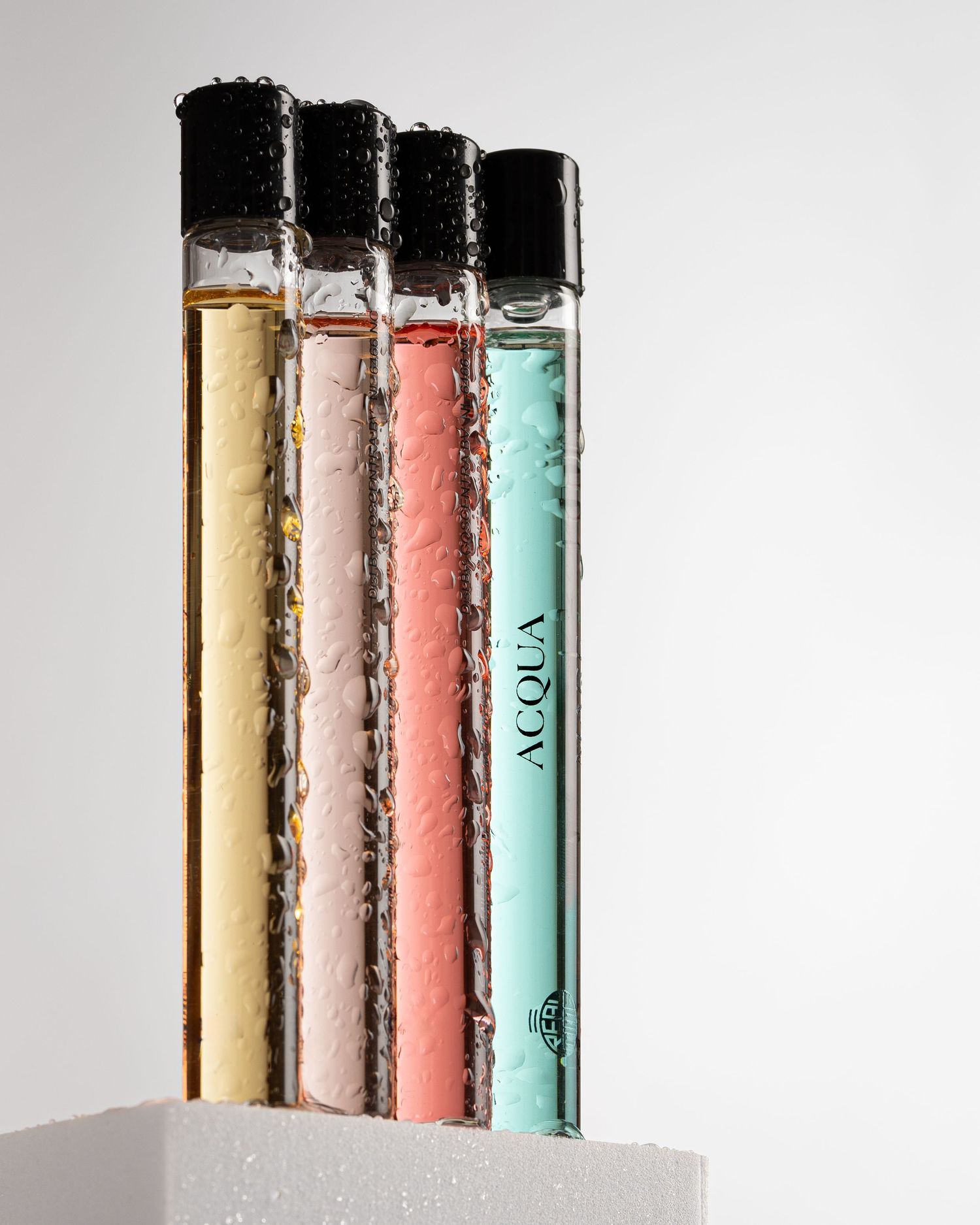 Four test tubes filled with different colored liquids arranged in a row against a white background.