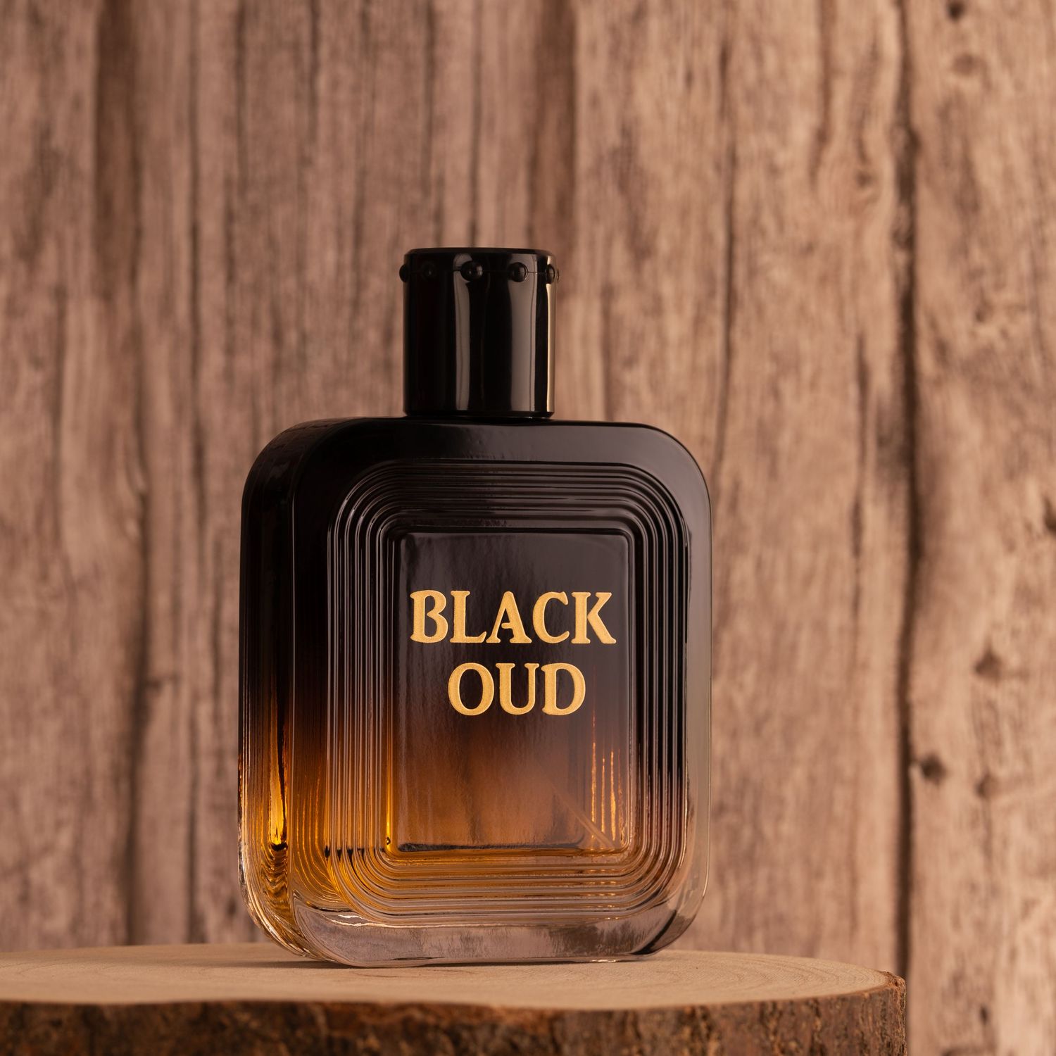 A bottle of Black Oud perfume with gradient design sitting on wooden shelf against rustic wooden background.