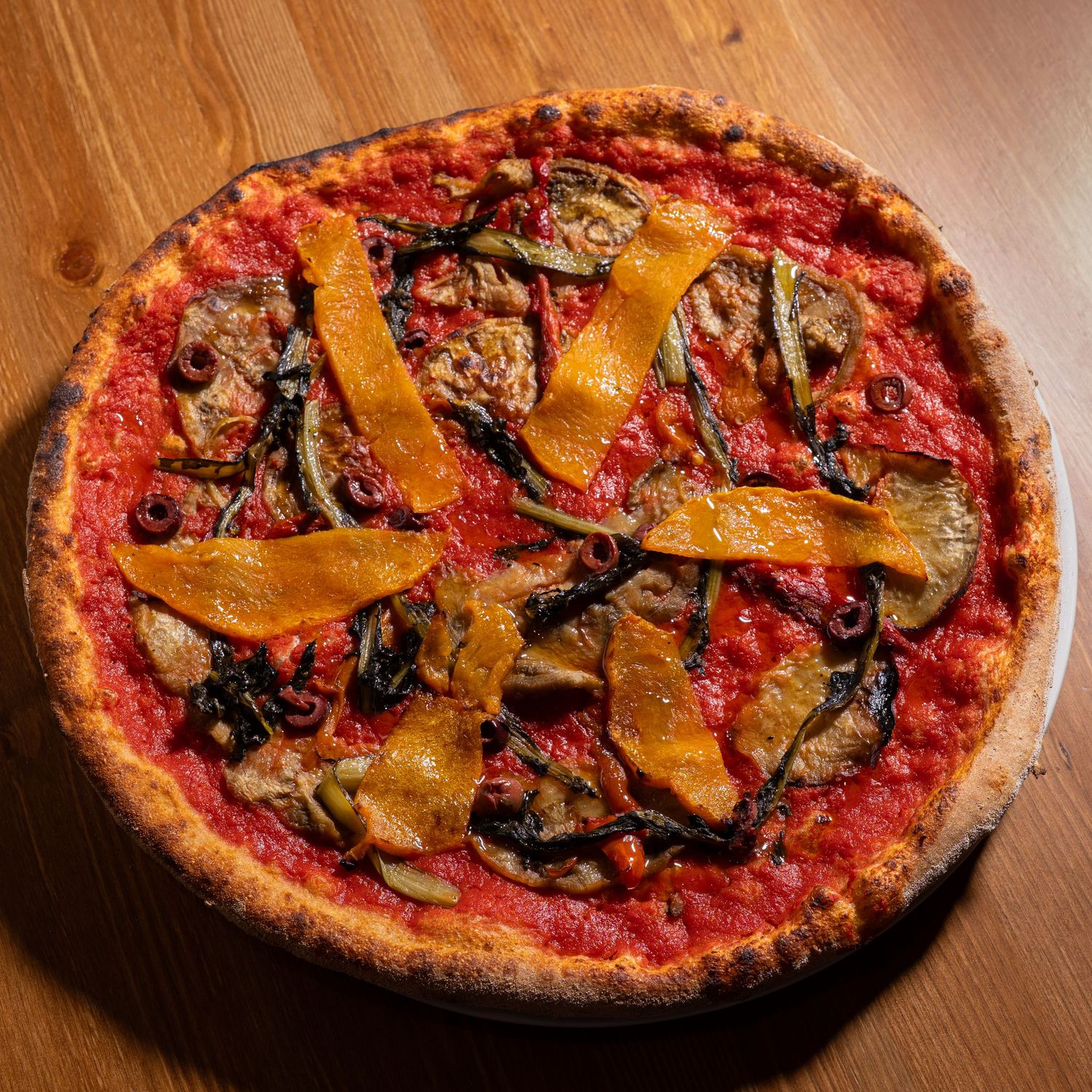 A homemade vegetarian pizza with roasted peppers and basil shown in progressive stages of being eaten from right to left.