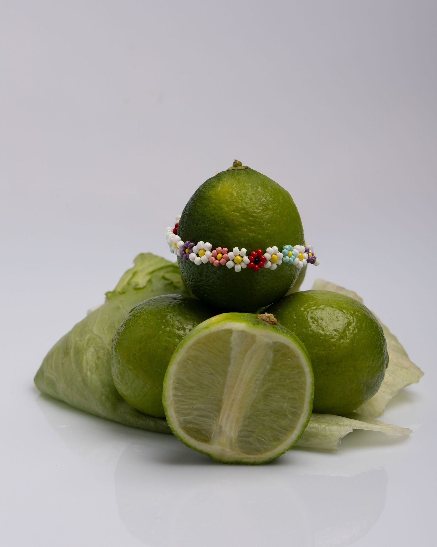 Four identical shots of fresh lime halves arranged in a minimalist composition against a plain gray background.