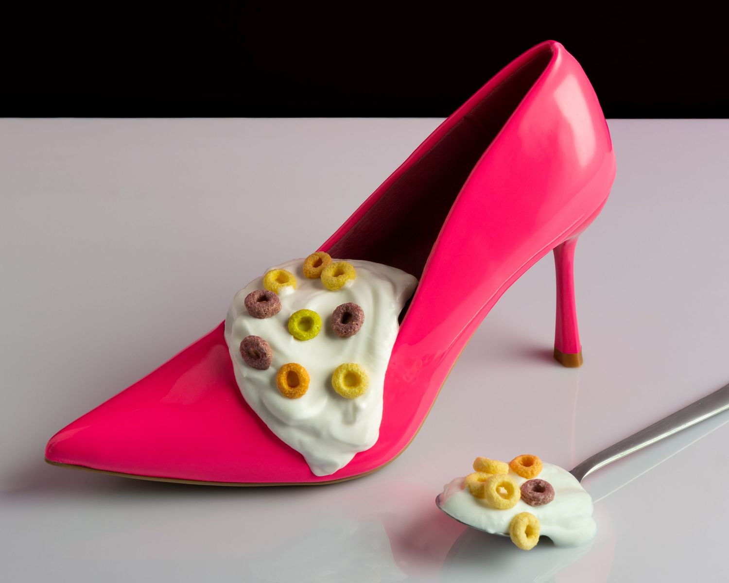 Hot pink high heel shoe displayed next to a decorative white skull ornament against a dark background.
